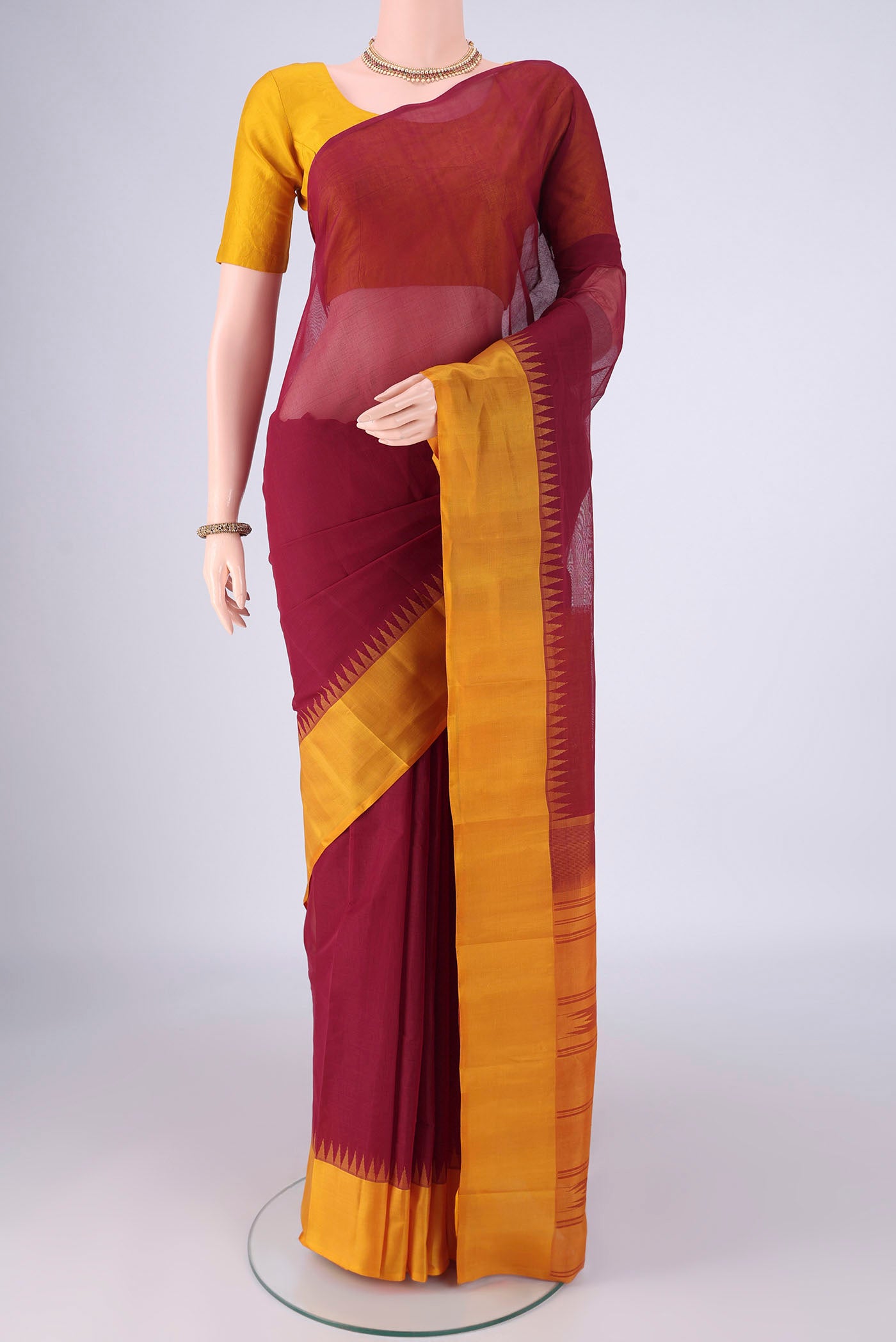 Maroon Kanchi Cotton Saree with Plain Body and Temple Thread Border.  displayed on a mannequin