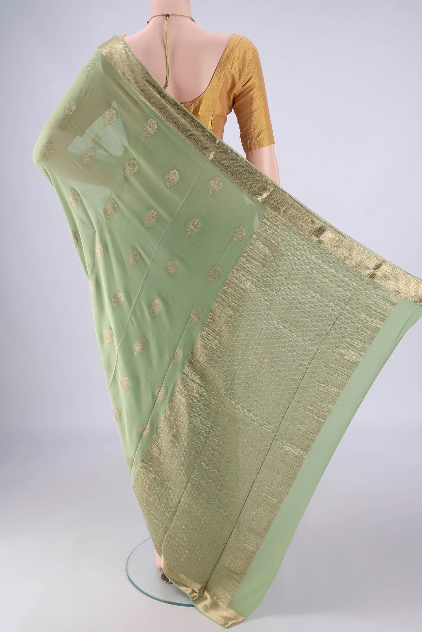 Flat view of Pista Green Mysore Georgette Saree with Zari Butta on the body and Zari Border. 