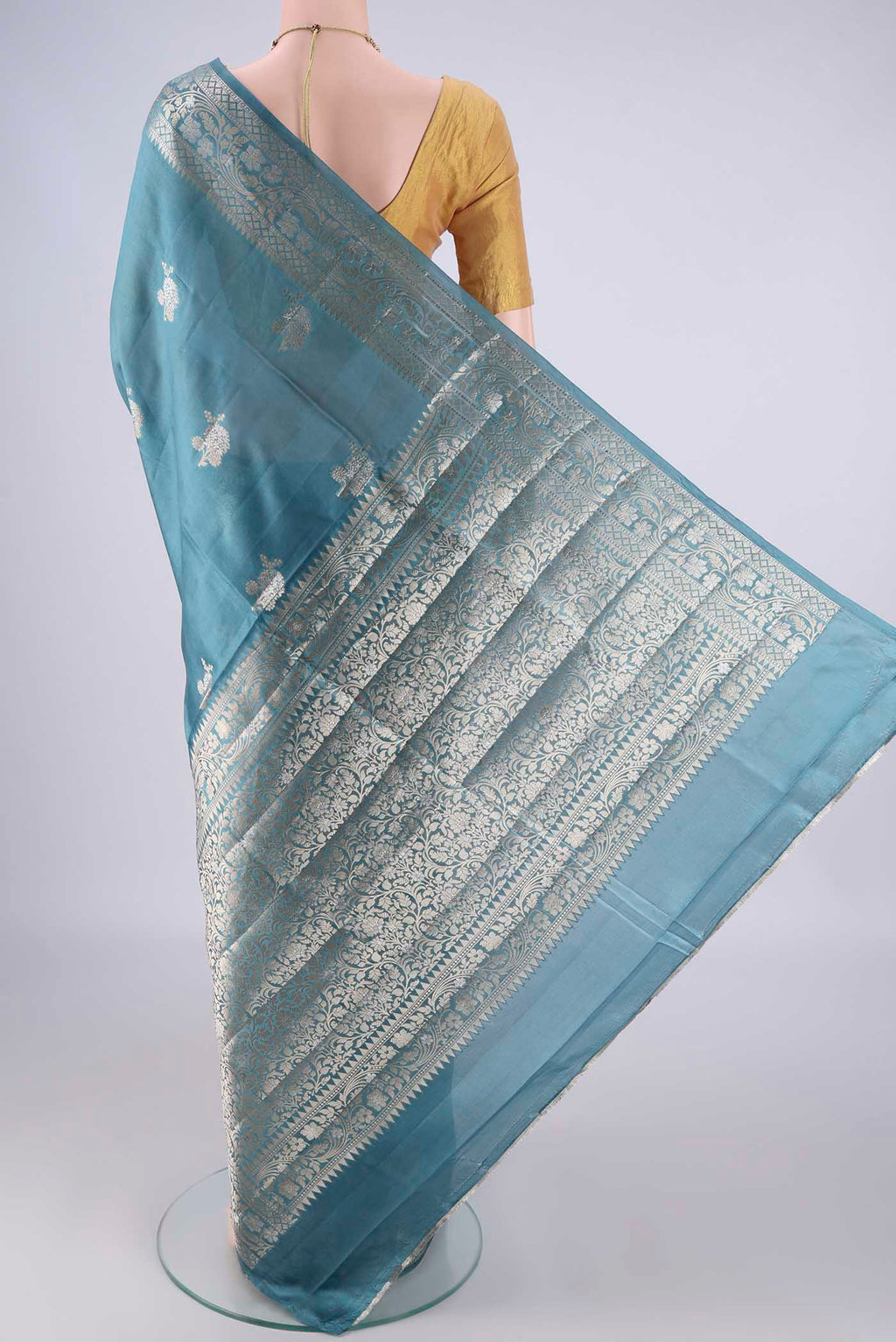 Flat view of Maya Blue Banarasi Raw Silk Saree with Zari Butta on the body and Zari Border. 