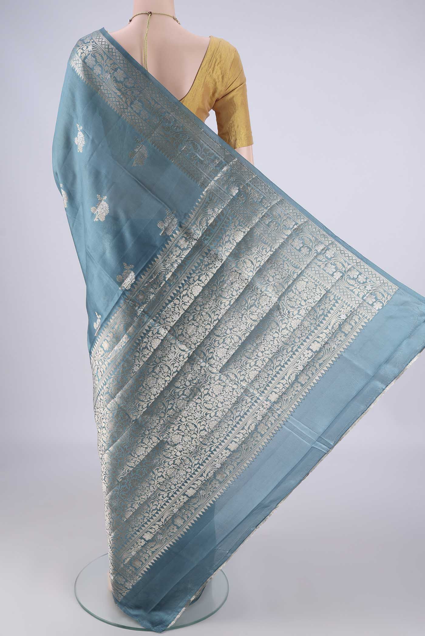Flat view of Maya Blue Banarasi Raw Silk Saree with Zari Butta on the body and Zari Border. 