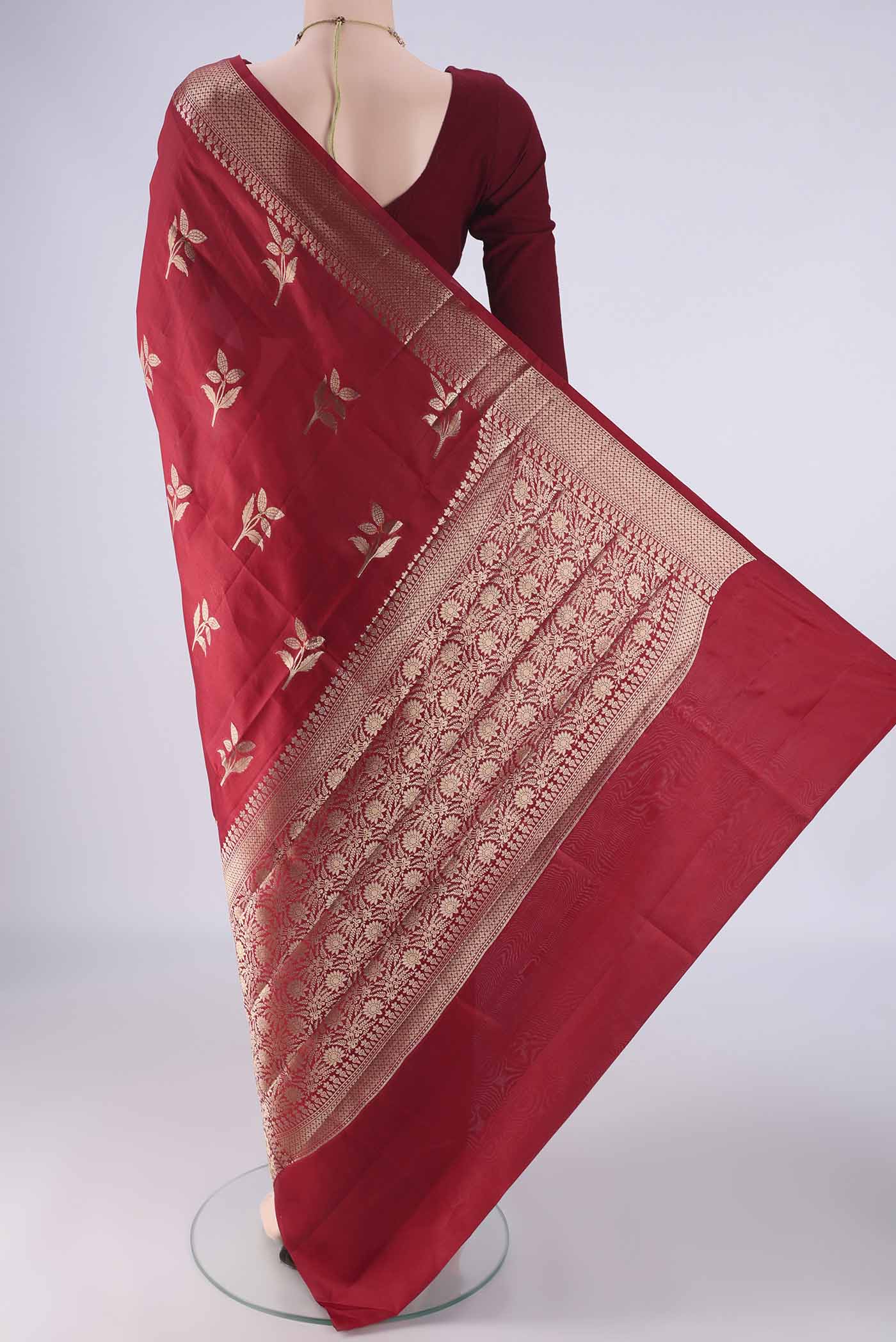 Flat view of Maroon Banarasi Raw Silk Saree with Zari Butta on the body and Zari And Thread Border. 