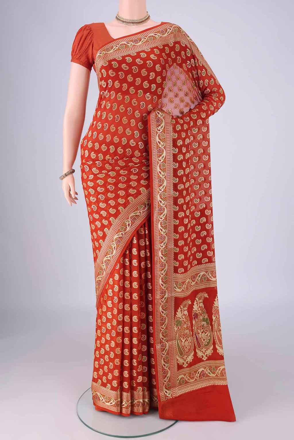 Brick Orange Blended Banarasi Georgette Saree with Thread Butta on the body and Zari And Thread Border.  displayed on a mannequin