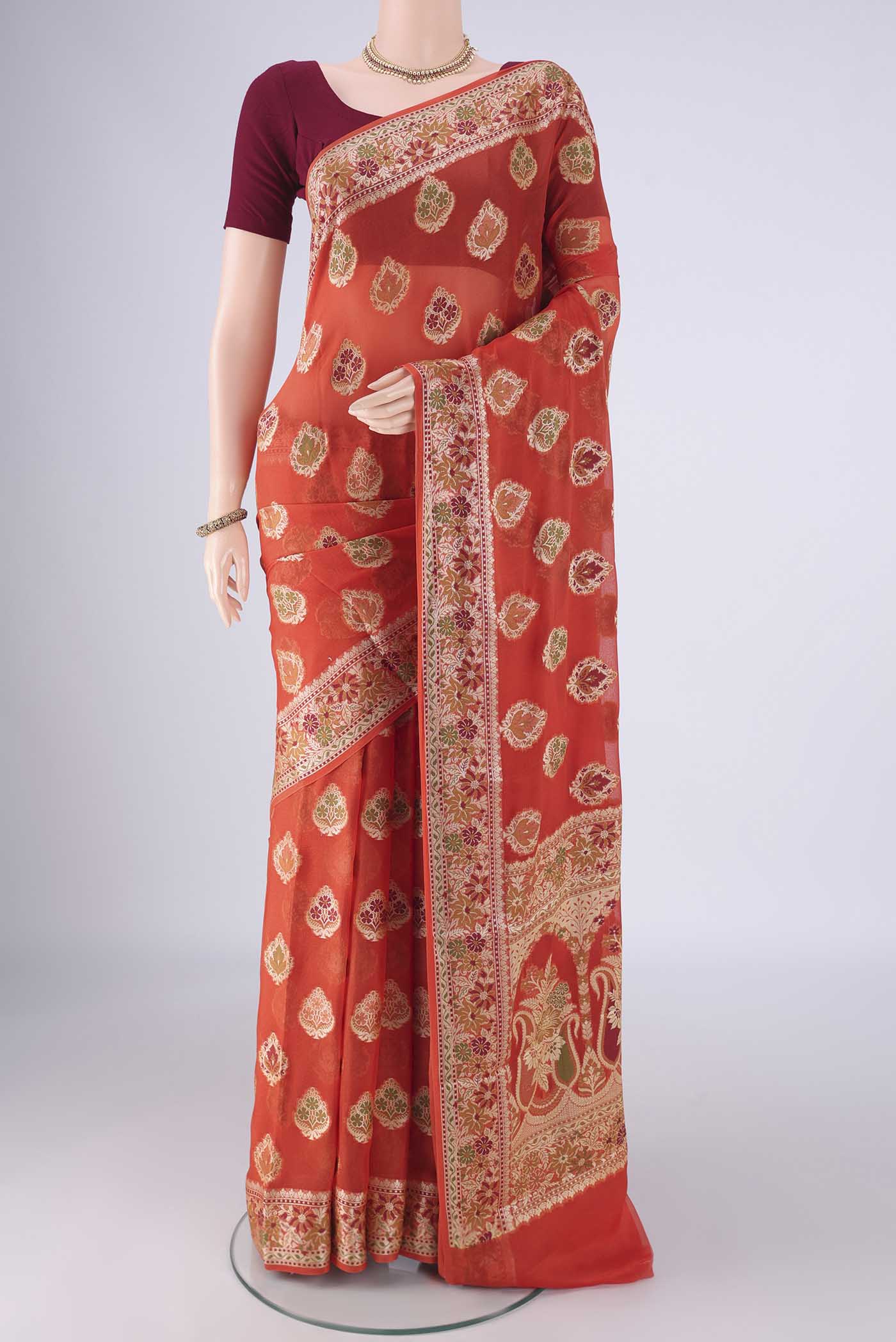 Rust Blended Banarasi Georgette Saree with Thread Butta on the body and Zari And Thread Border.  displayed on a mannequin