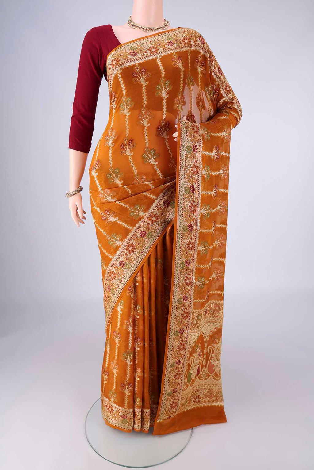 Mustard Blended Banarasi Georgette Saree with Zari And Thread Butta on the body and Zari And Thread Border.  displayed on a mannequin