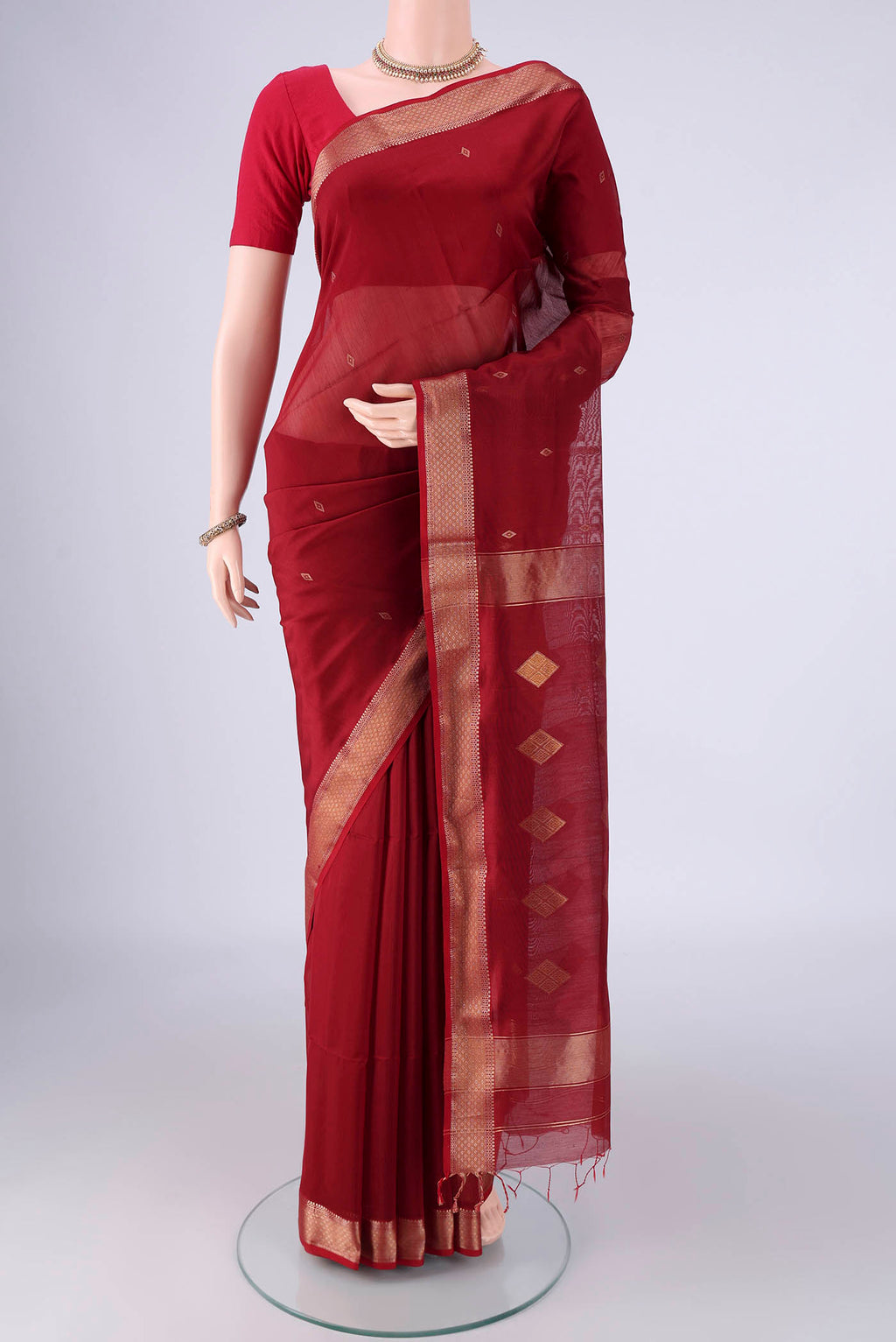 Maroon Maheshwari Silk Cotton Saree with Zari Butta on the body and Zari Border.  displayed on a mannequin