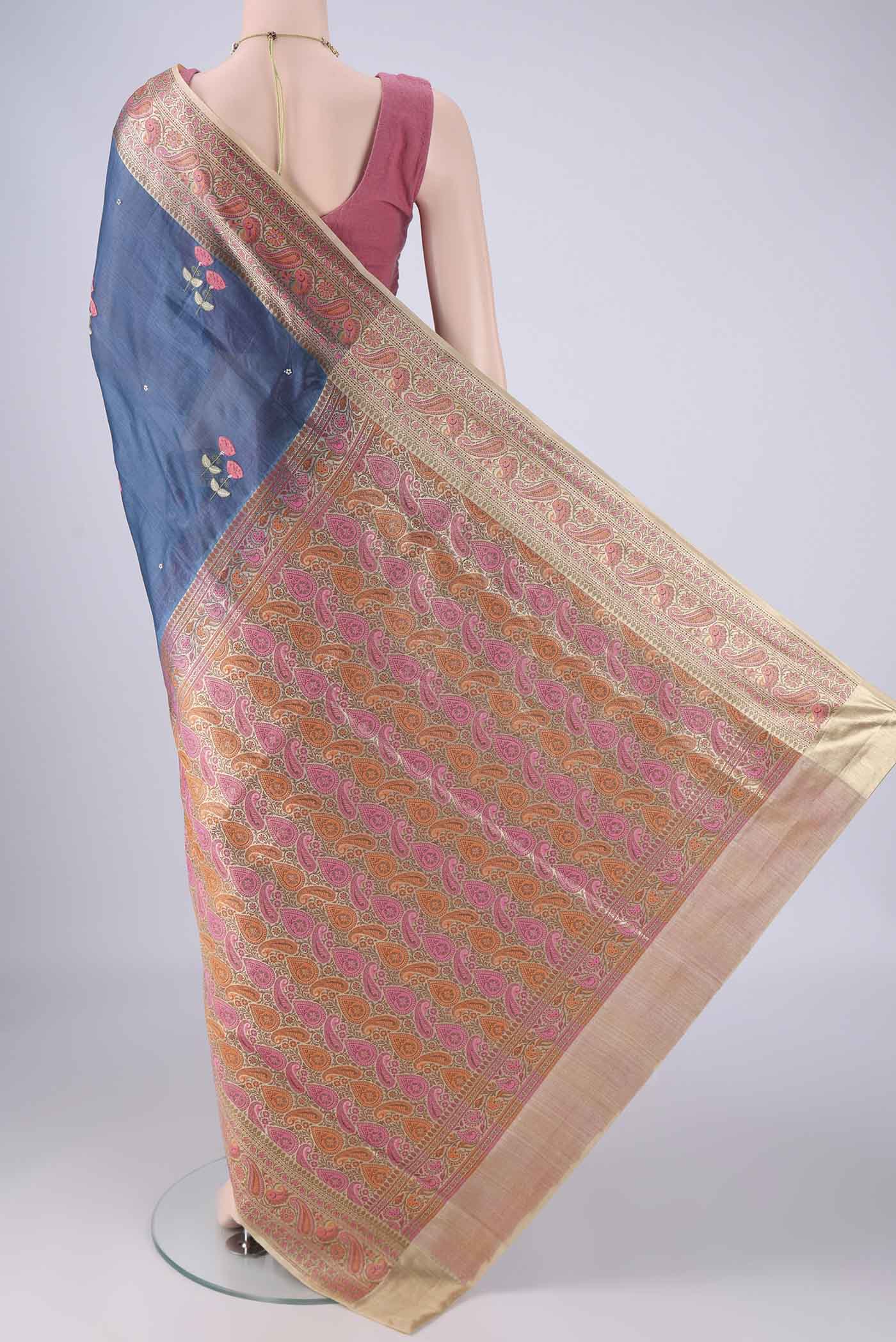 Flat view of Blue Banarasi Tussar Silk Saree with Embroidery on the body and Zari Border. 