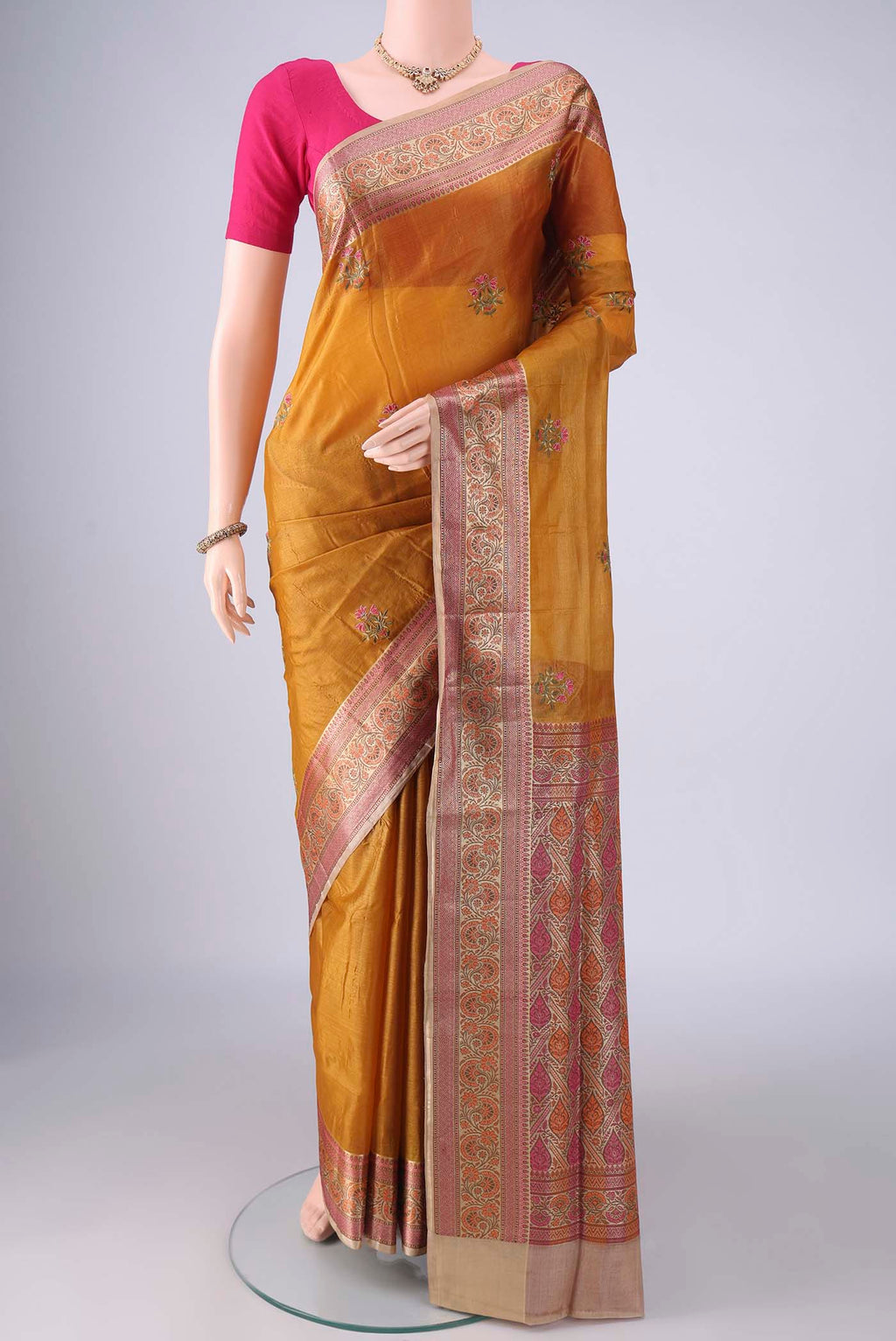 Mustard Banarasi Tussar Saree with Embroidery on the body and Zari Border.  displayed on a mannequin
