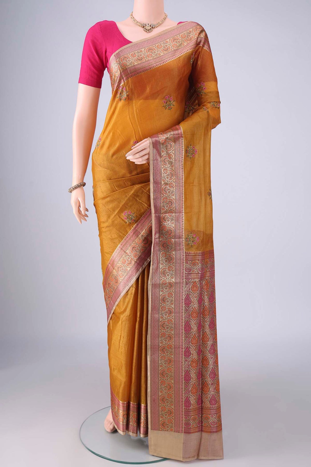 Mustard Banarasi Tussar Saree with Embroidery on the body and Zari Border.  displayed on a mannequin