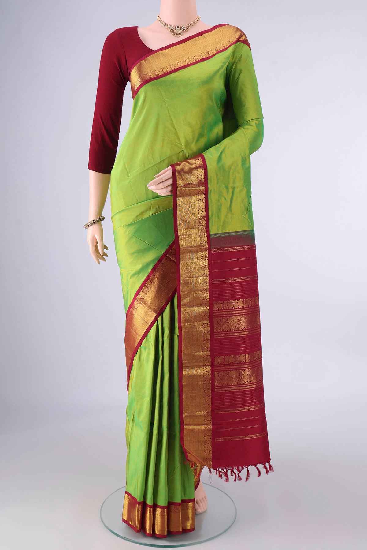 Pure Silk Parrot Green Kanjivaram Saree with Plain Body and Zari Border.  displayed on a mannequin