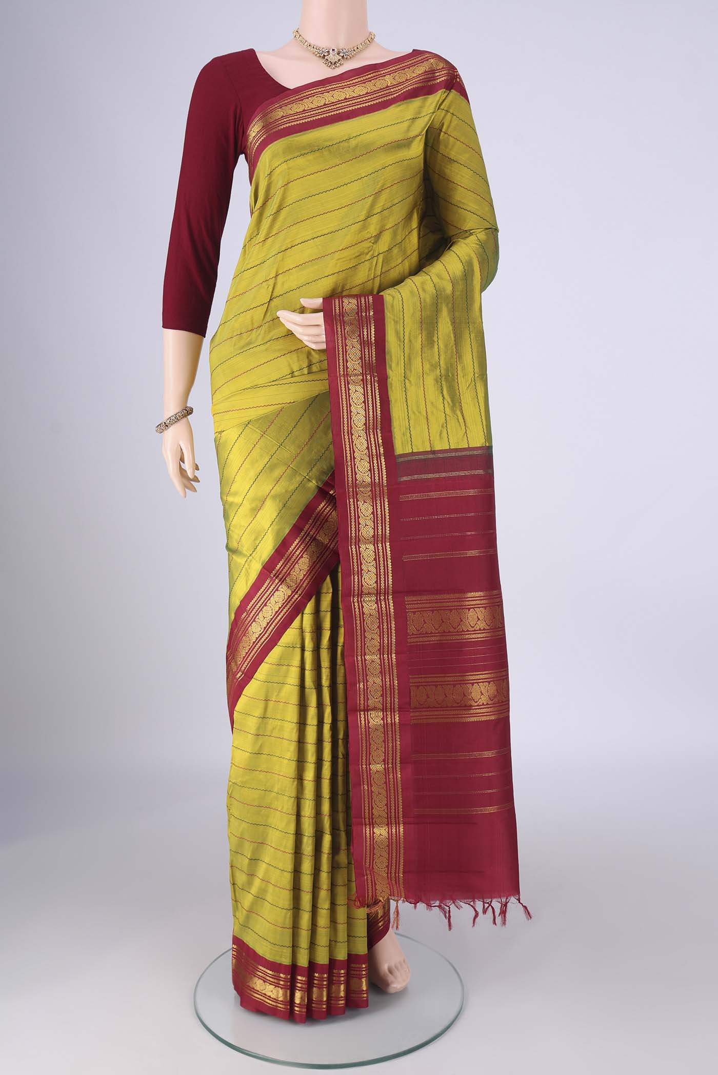Green Kanchipuram Silk Saree with Stripes on the body and Zari Border.  displayed on a mannequin