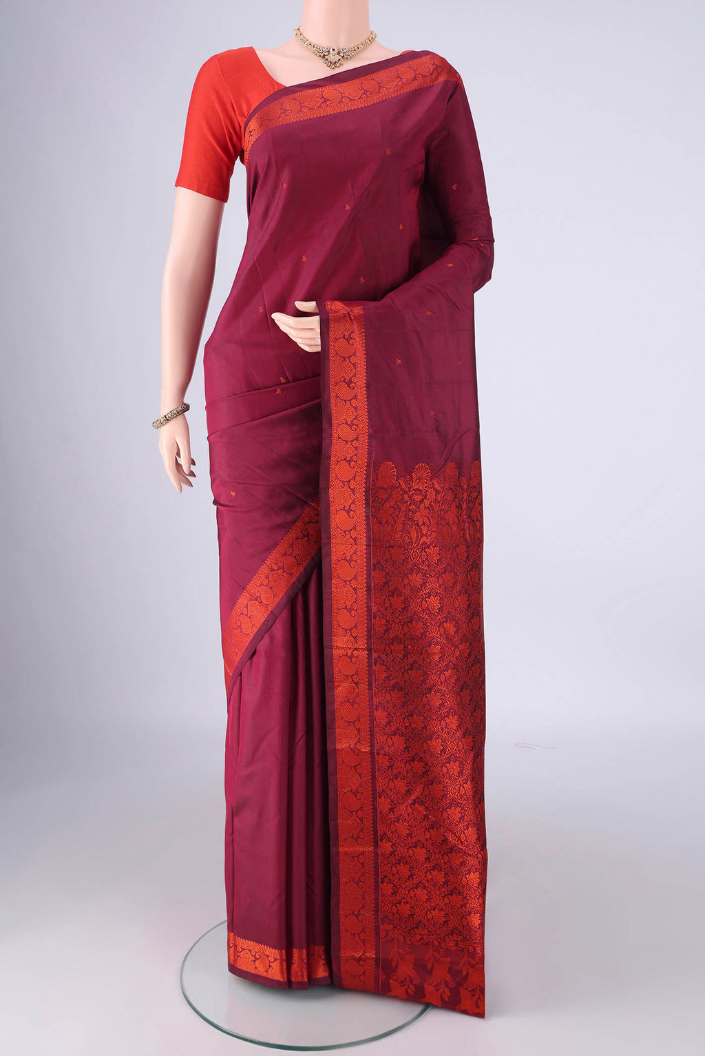 Maroon Kanchipuram Silk Saree with Thread Butta on the body and Thread Border.  displayed on a mannequin