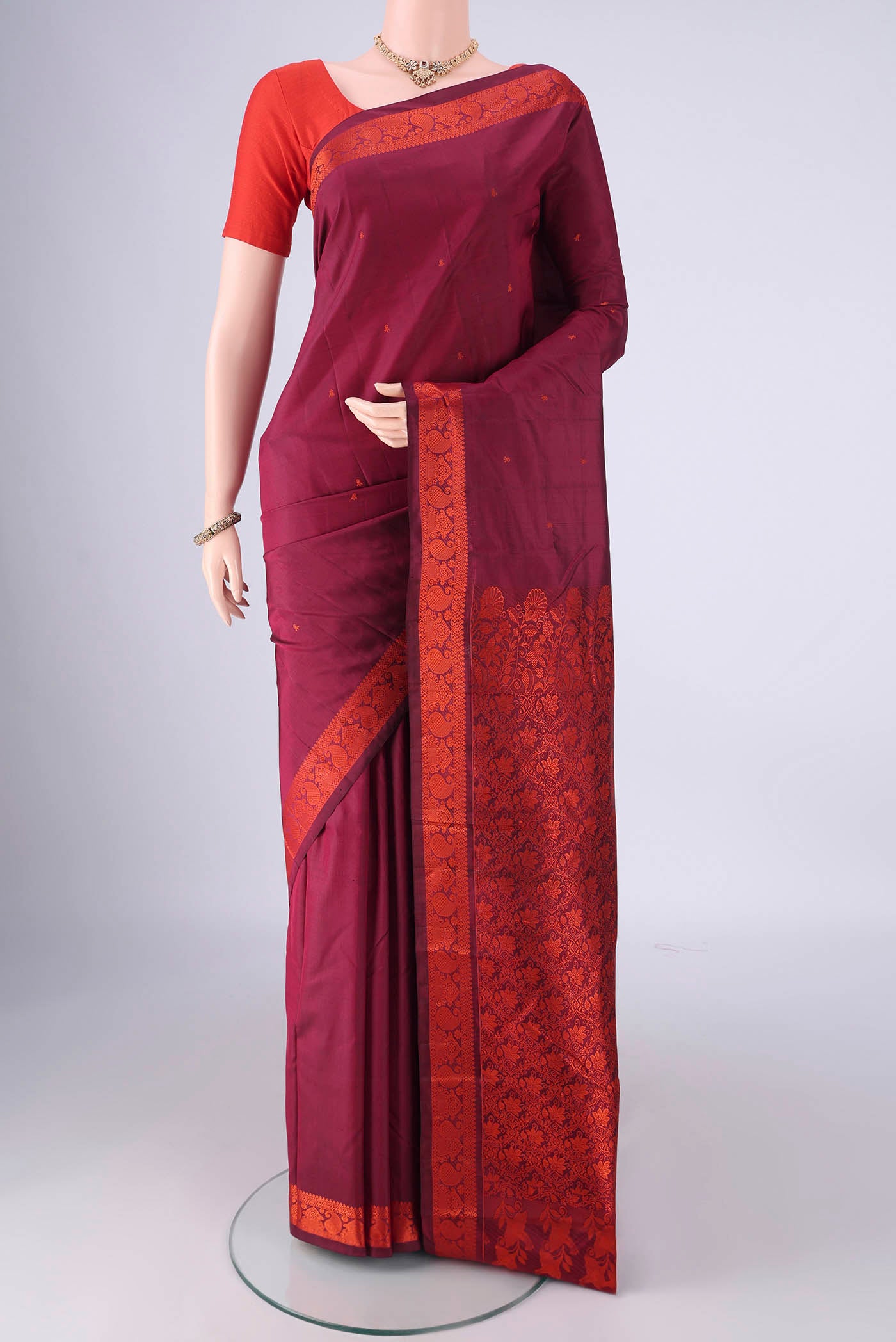 Maroon Kanchipuram Silk Saree with Thread Butta on the body and Thread Border.  displayed on a mannequin