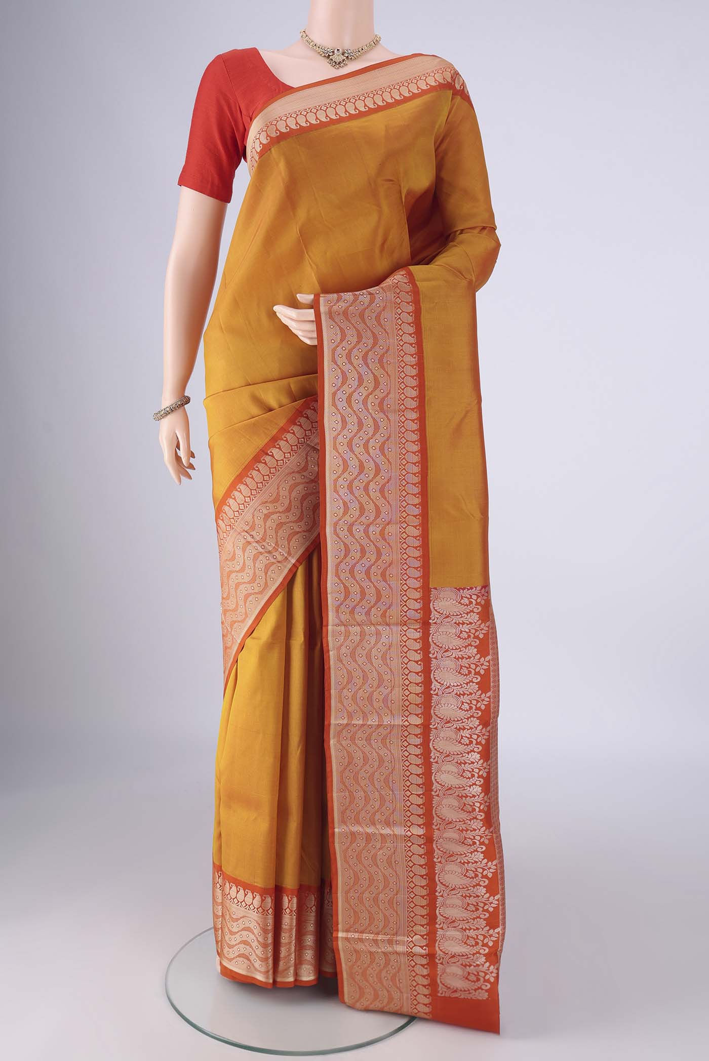 Mustard Kanjivaram Silk Saree with Plain Body and Thread Border.  displayed on a mannequin
