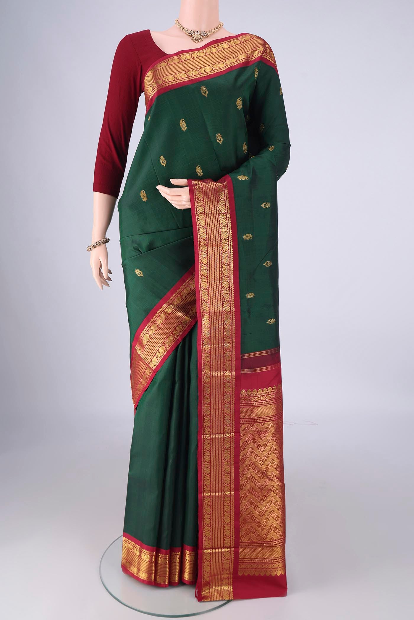Green Kanchipuram Silk Saree with Zari Butta on the body and Zari Border.  displayed on a mannequin