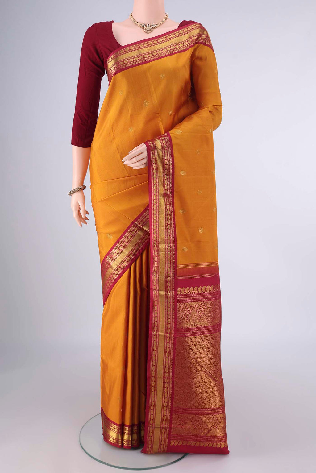 Pure Silk Mustard Kanchipuram Saree with Zari Butta on the body and Zari Border.  displayed on a mannequin