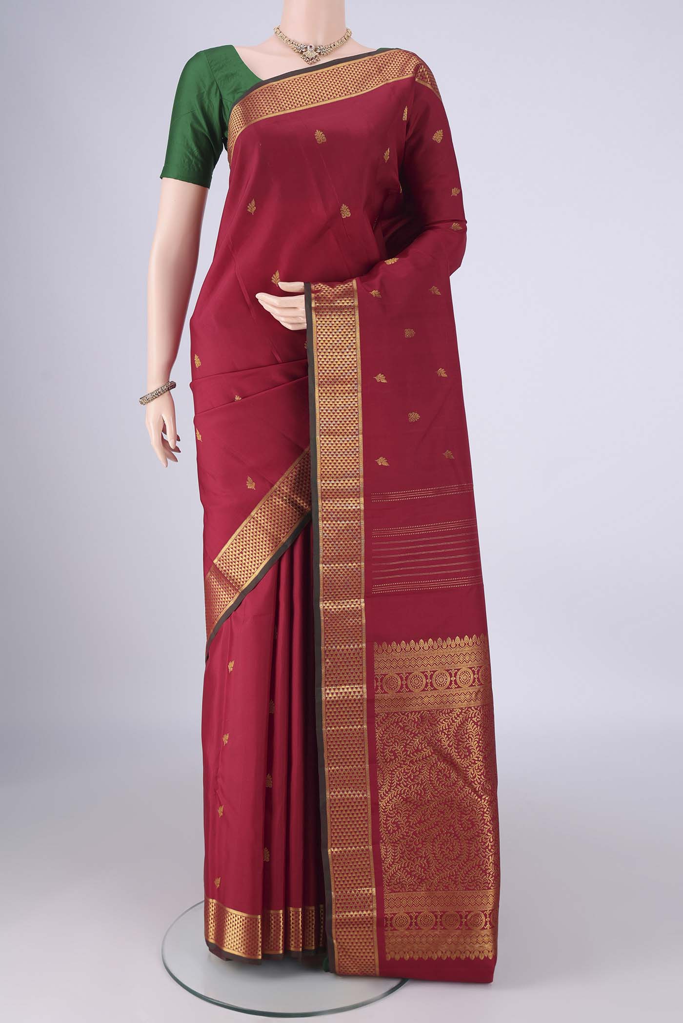 Maroon Kanchipuram Silk Saree with Zari Butta on the body and Zari Border.  displayed on a mannequin