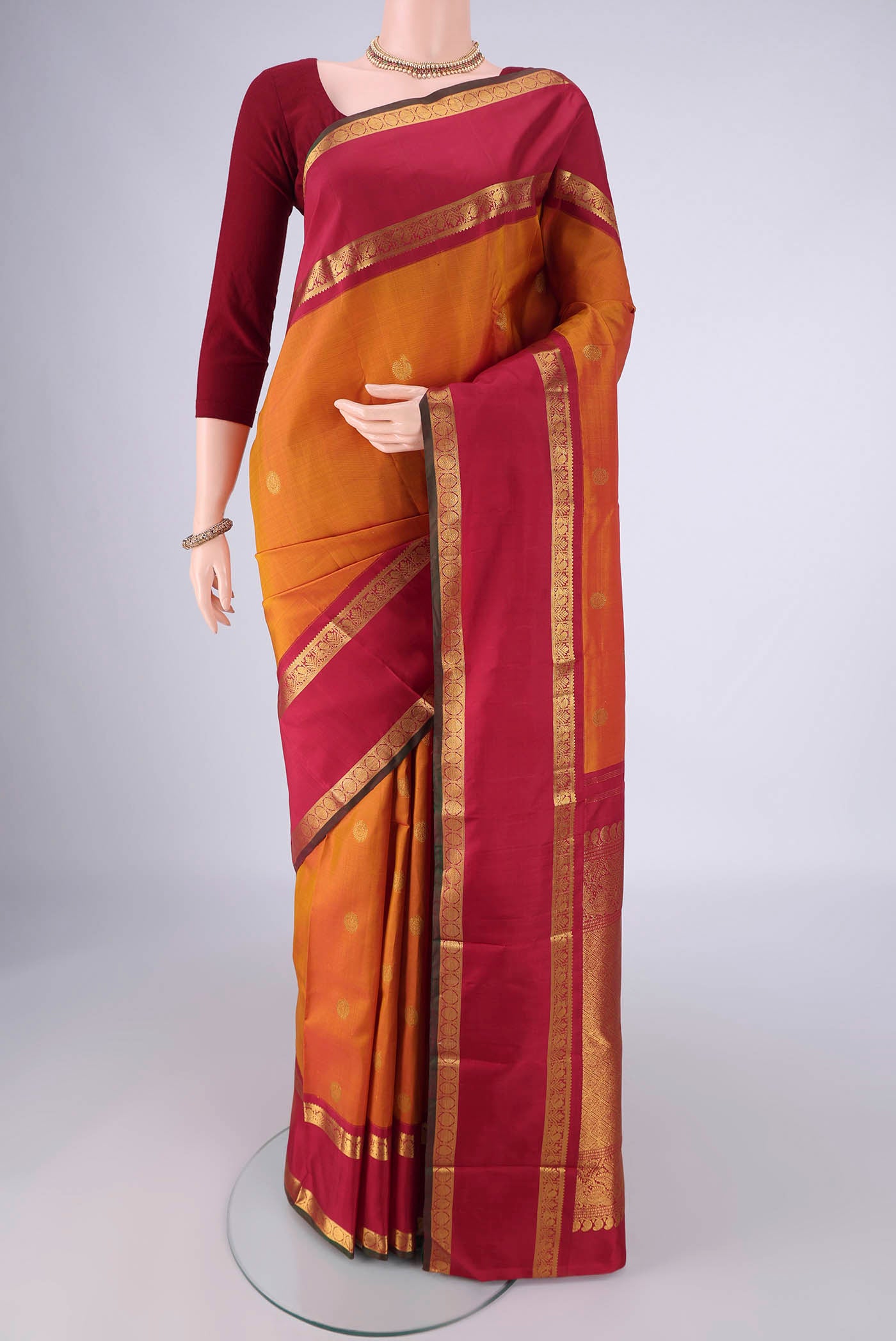 Mustard Kanchipuram Silk Saree with Zari Butta on the body and Zari Border.  displayed on a mannequin