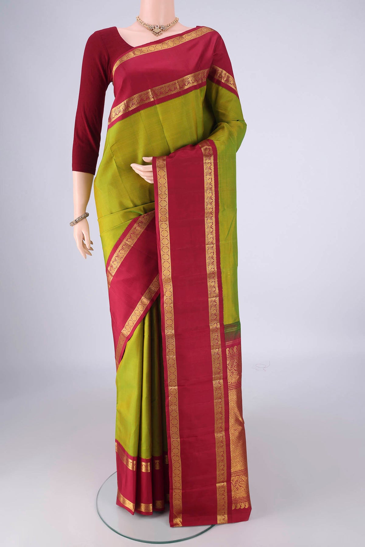 Green Kanchipuram Silk Saree with Zari Butta on the body and Zari Border.  displayed on a mannequin