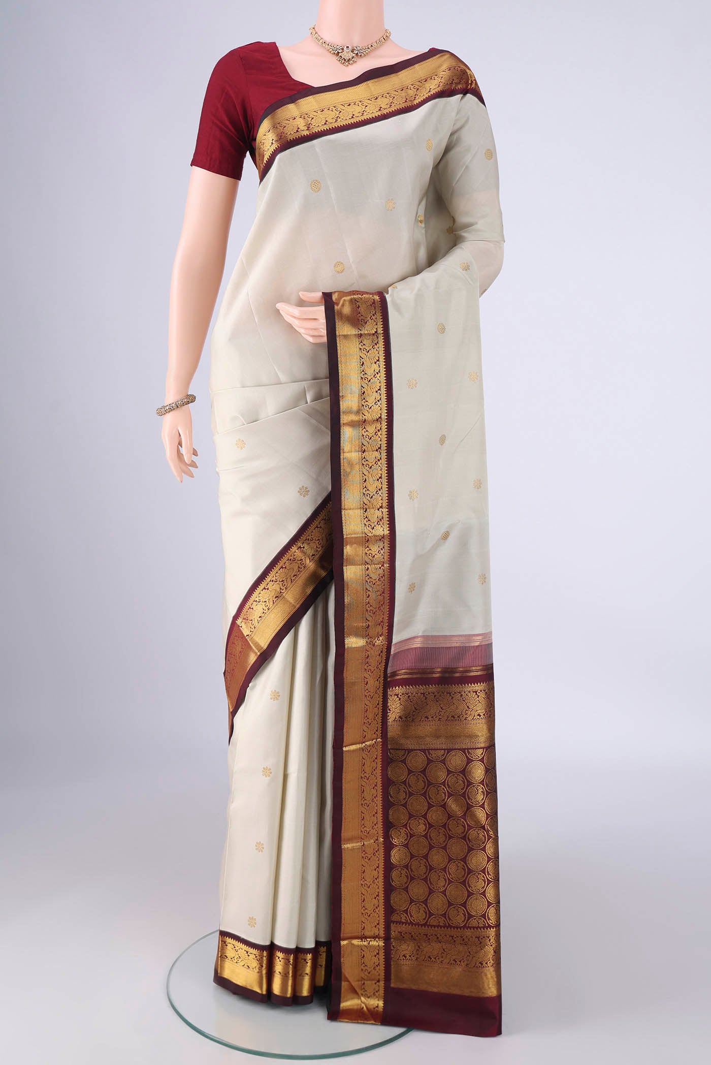 Off White Kanchipuram Silk Saree with Zari Butta on the body and Zari Border.  displayed on a mannequin