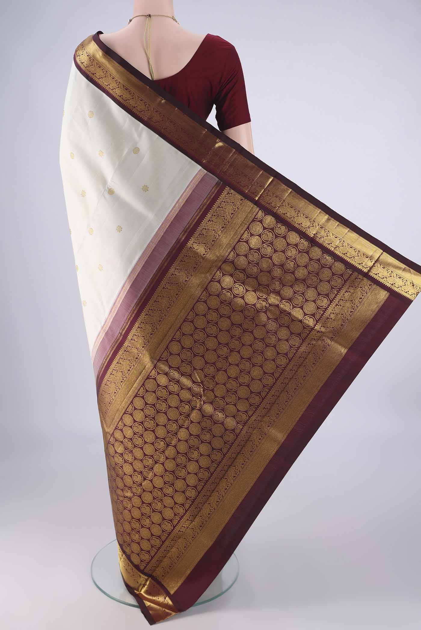 Flat view of Off White Kanchipuram Silk Saree with Zari Butta on the body and Zari Border. 
