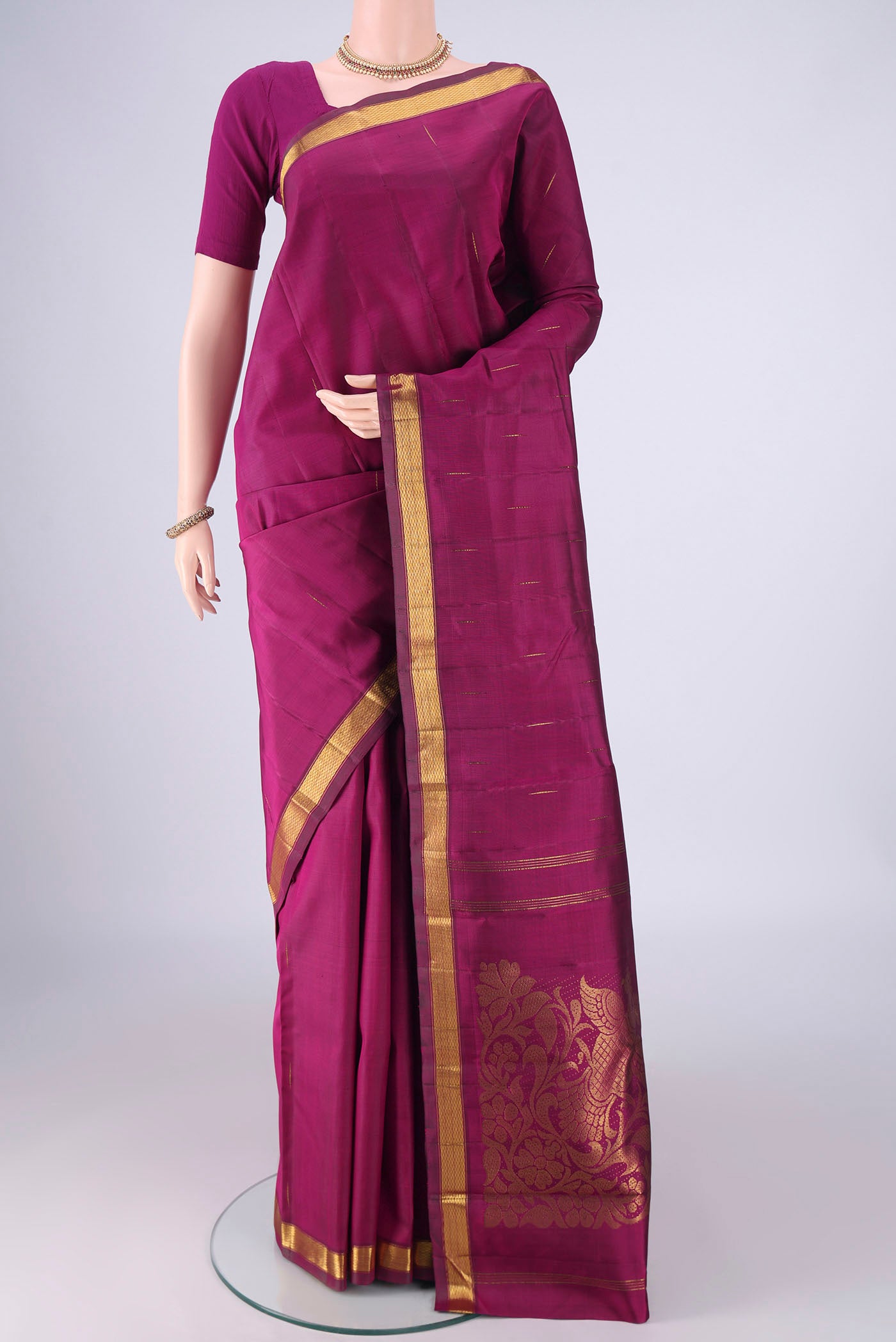 Magenta Kanjivaram Silk Saree with Zari Butta on the body and Zari Border.  displayed on a mannequin