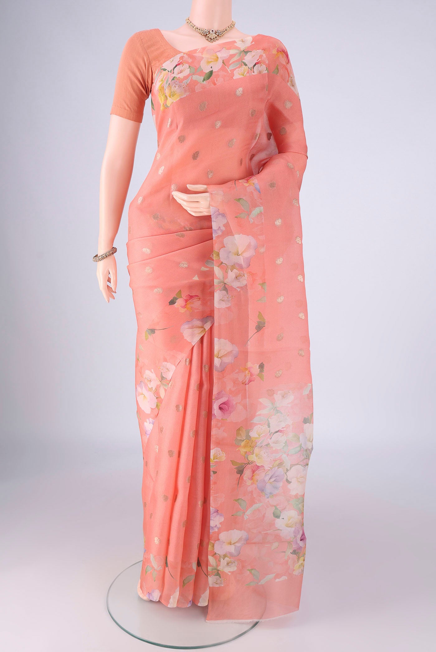 Peach Organza Silk Saree with Zari Butta on the body and Printed Border.  displayed on a mannequin