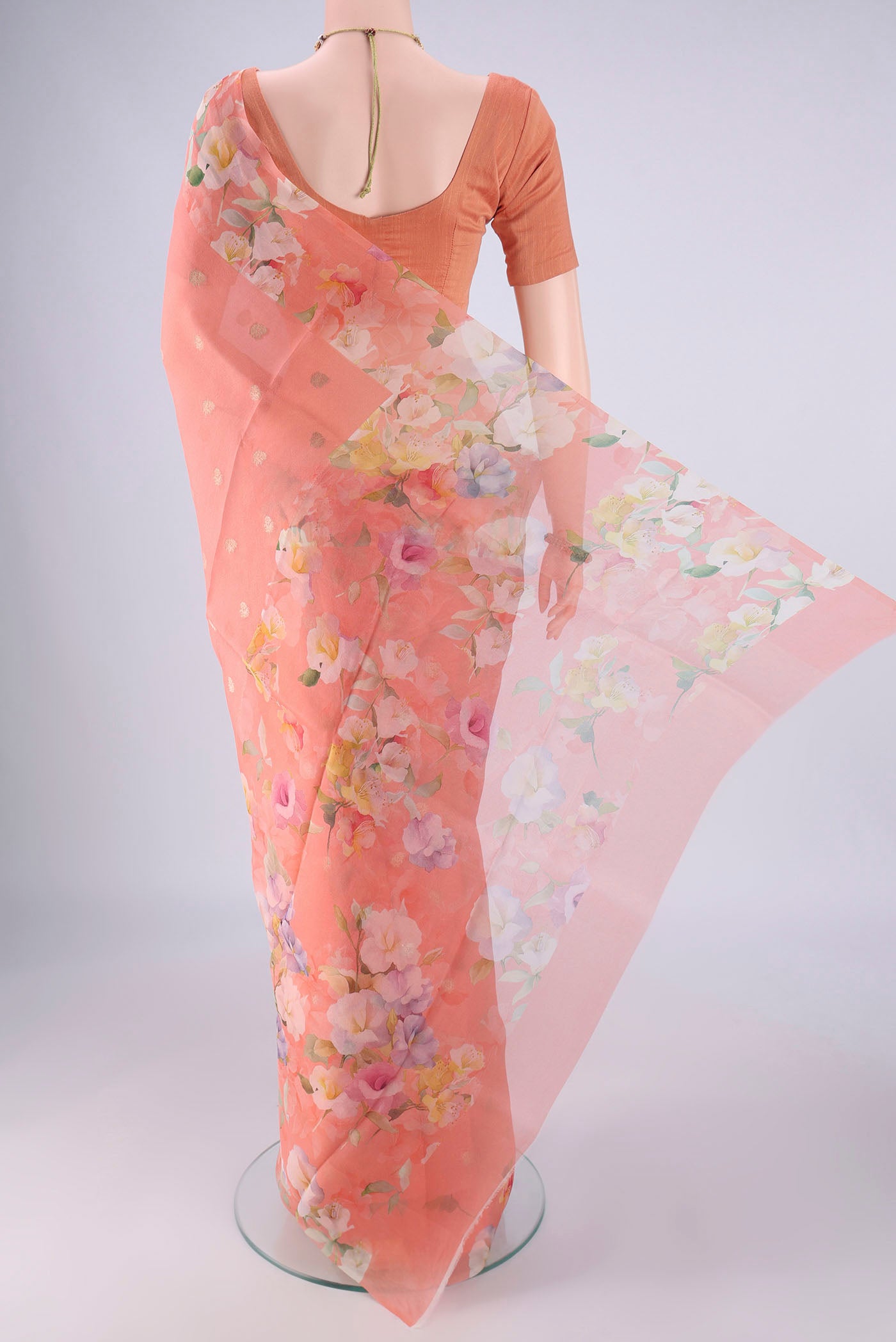 Flat view of Peach Organza Silk Saree with Zari Butta on the body and Printed Border. 
