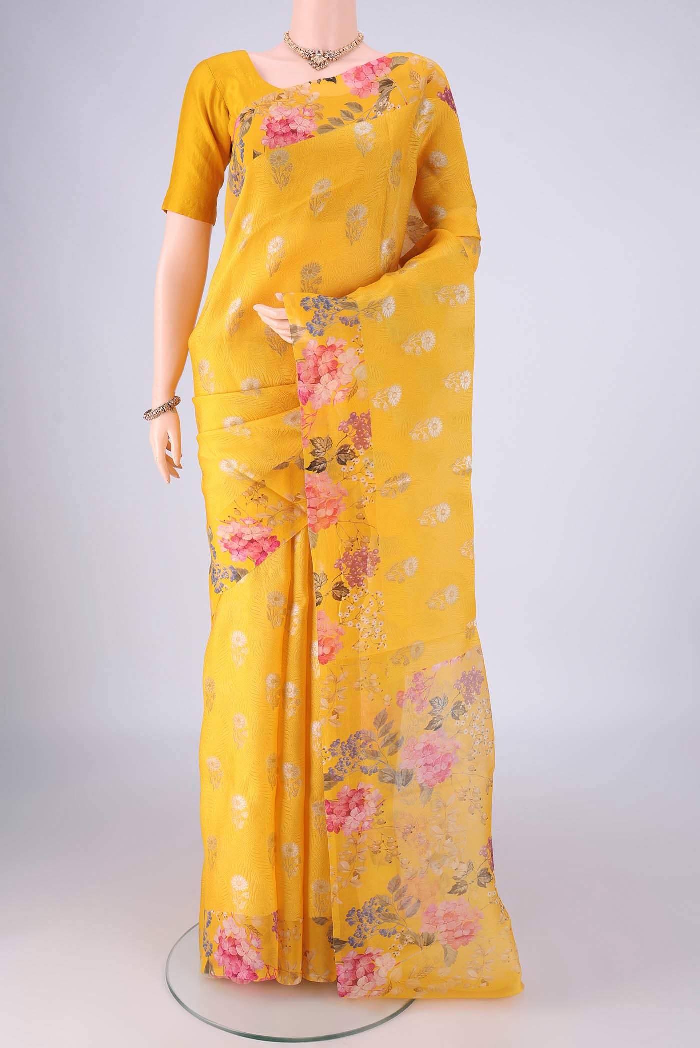 Yellow Organza Silk Saree with Zari Butta on the body and Printed Border.  displayed on a mannequin