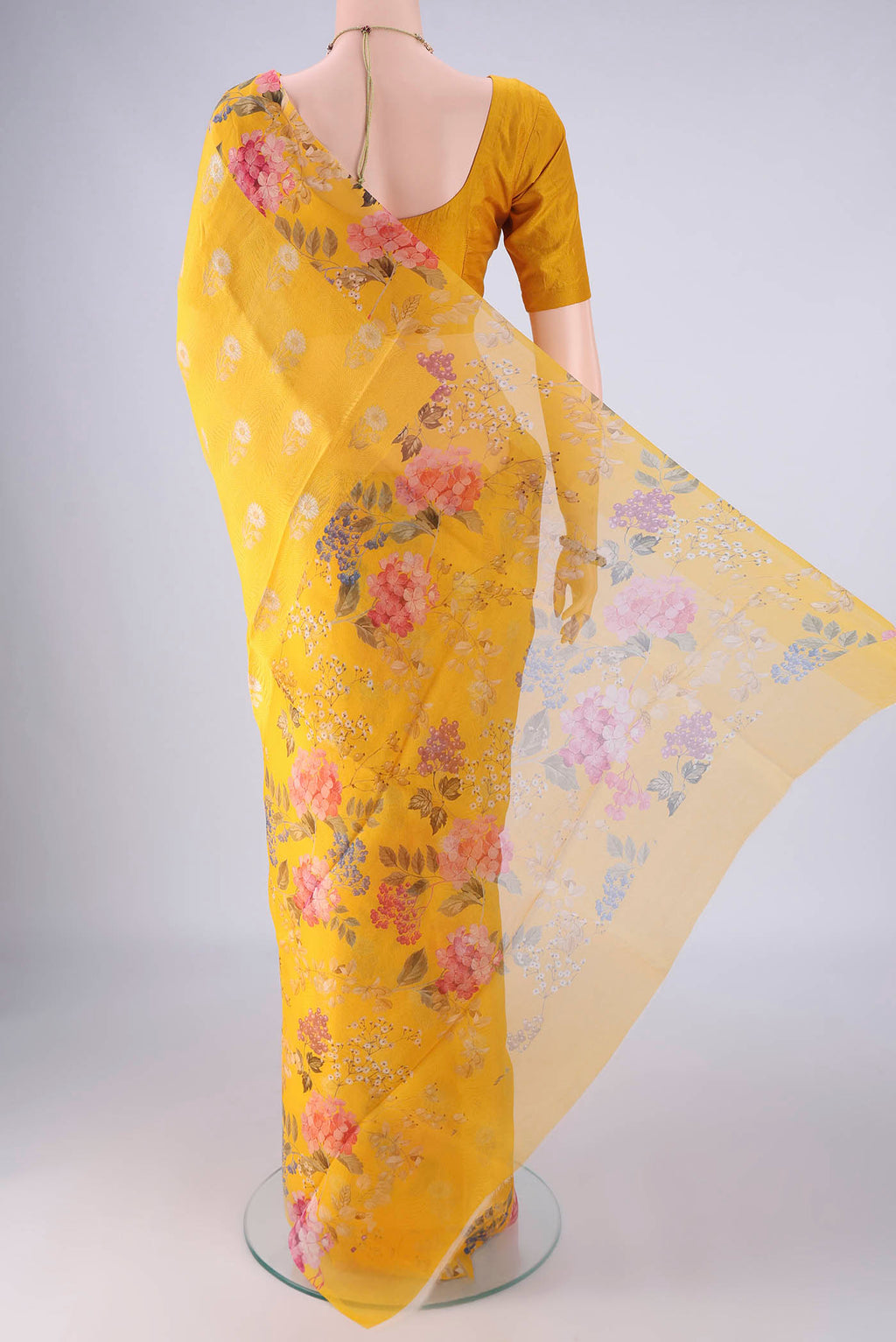 Flat view of Yellow Organza Silk Saree with Zari Butta on the body and Printed Border. 