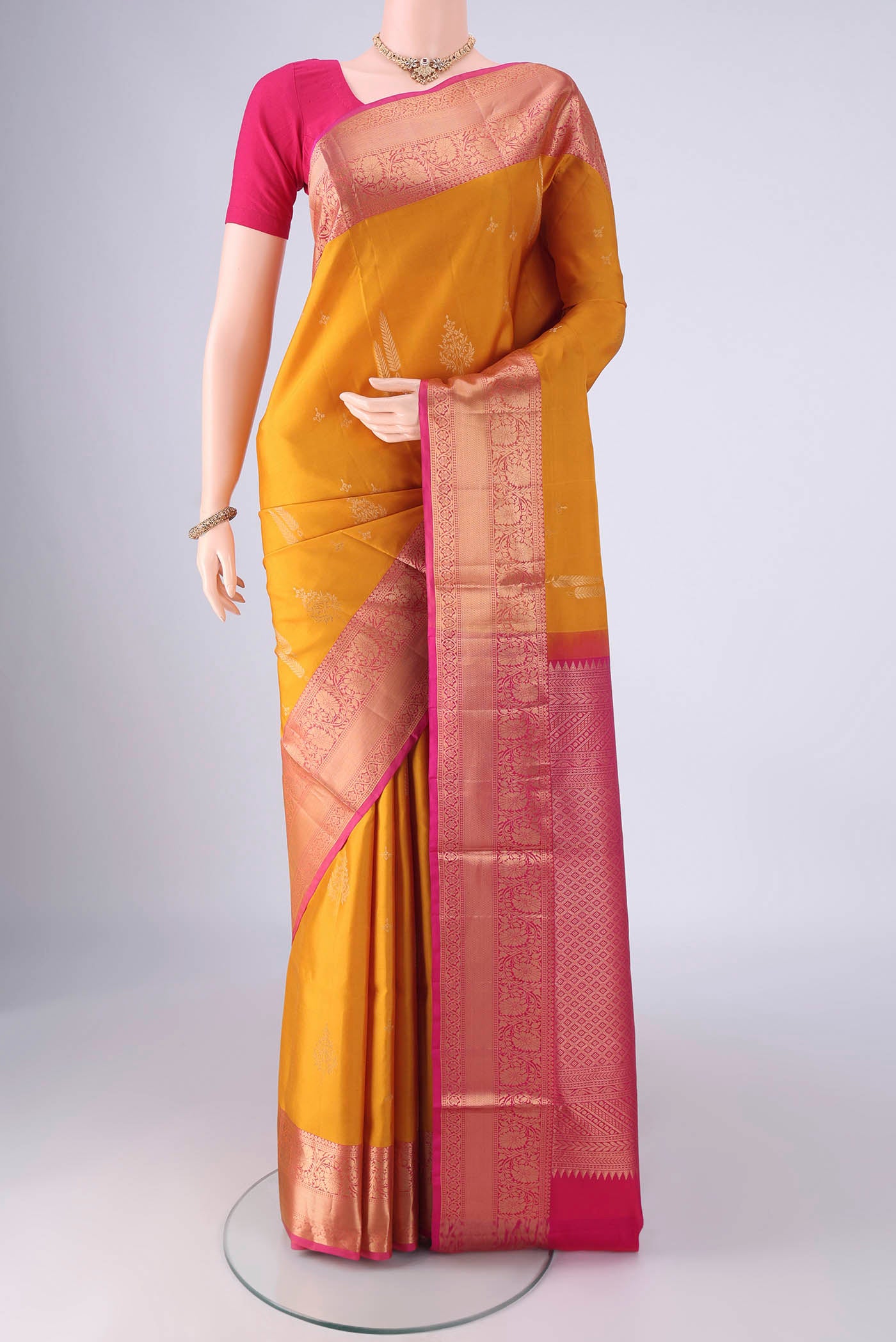 Mustard Soft Silk Saree with Zari Butta on the body and Zari Border.  displayed on a mannequin