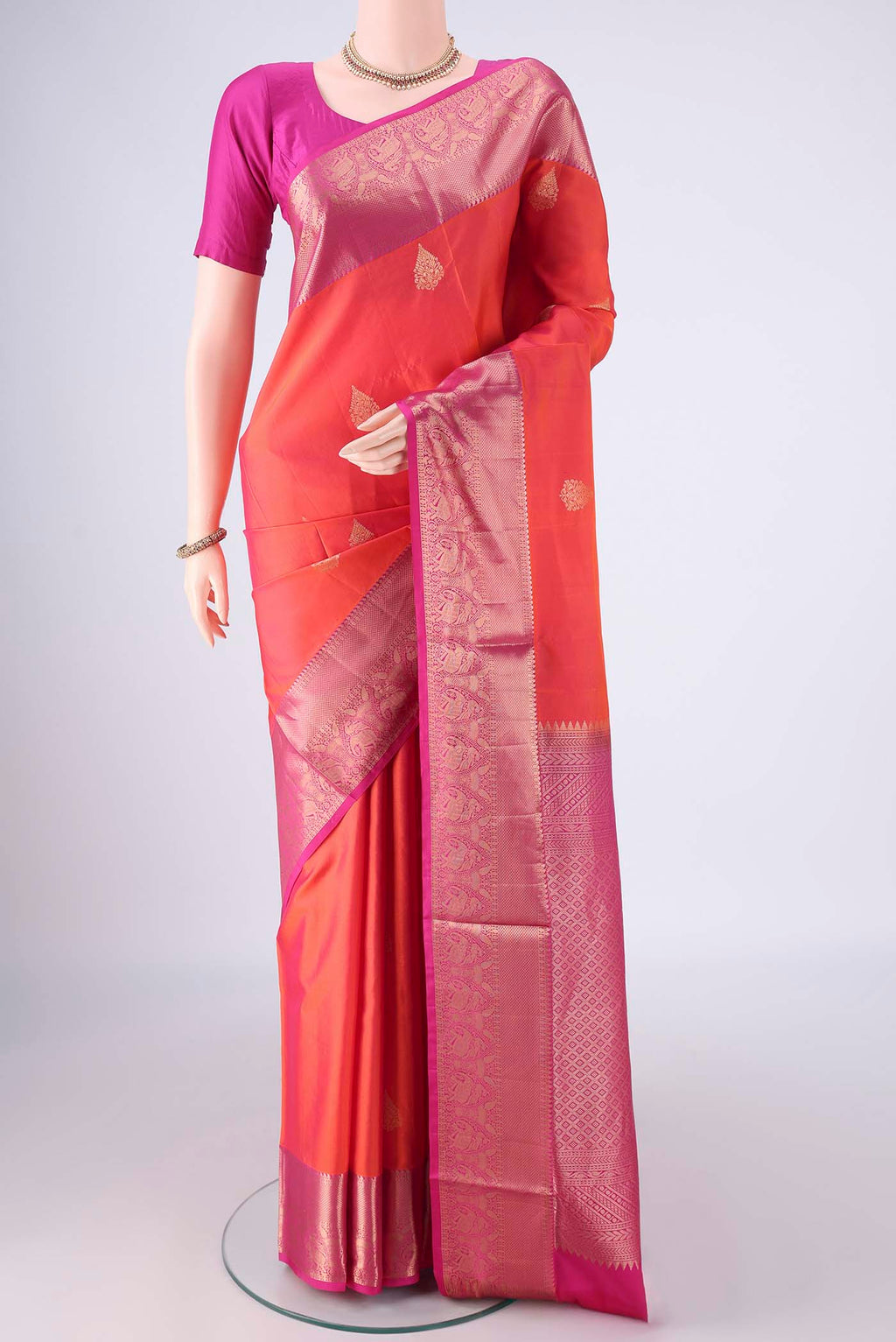 Orange Soft Silk Saree with Zari Butta on the body and Zari Border.  displayed on a mannequin