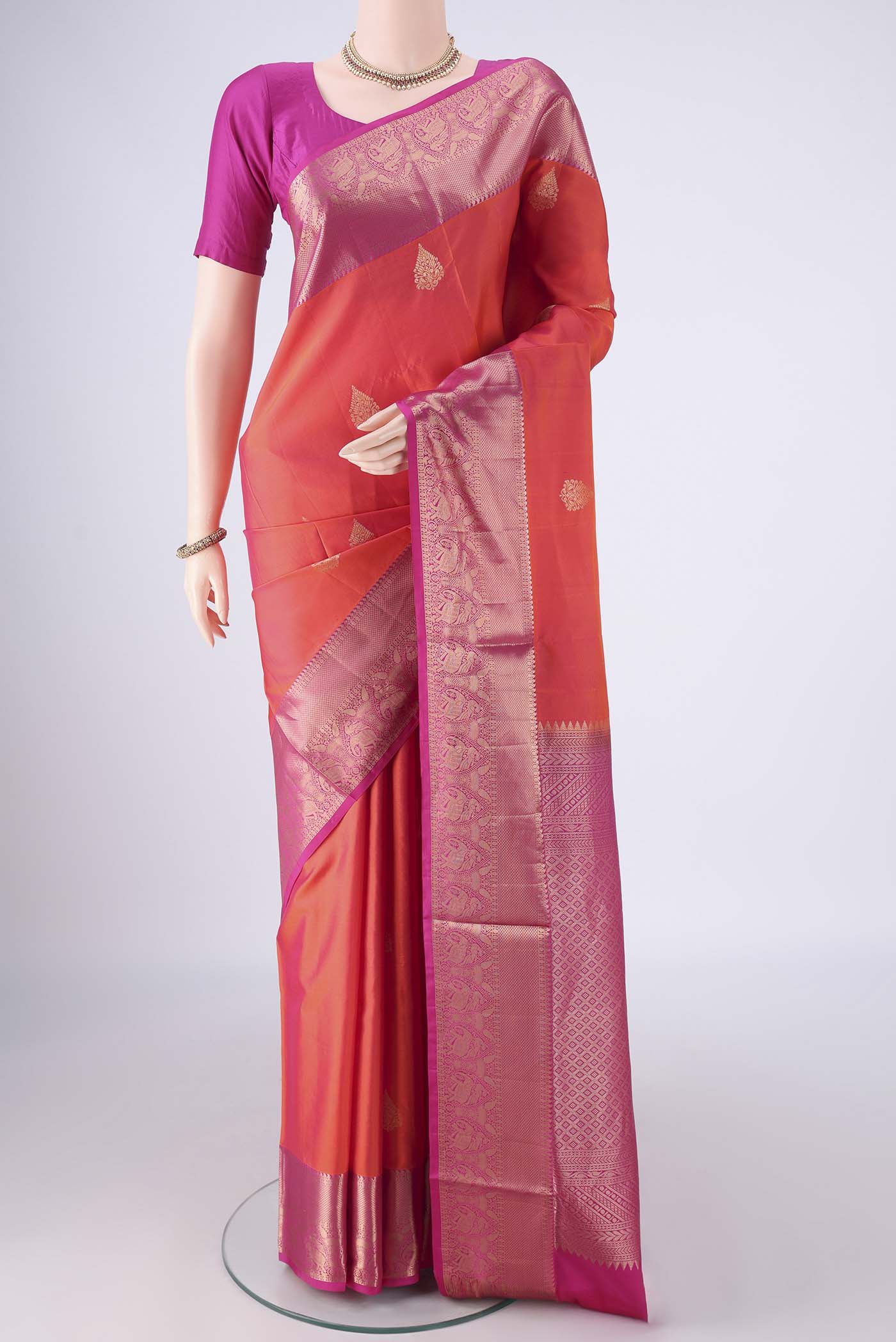 Orange Soft Silk Saree with Zari Butta on the body and Zari Border.  displayed on a mannequin