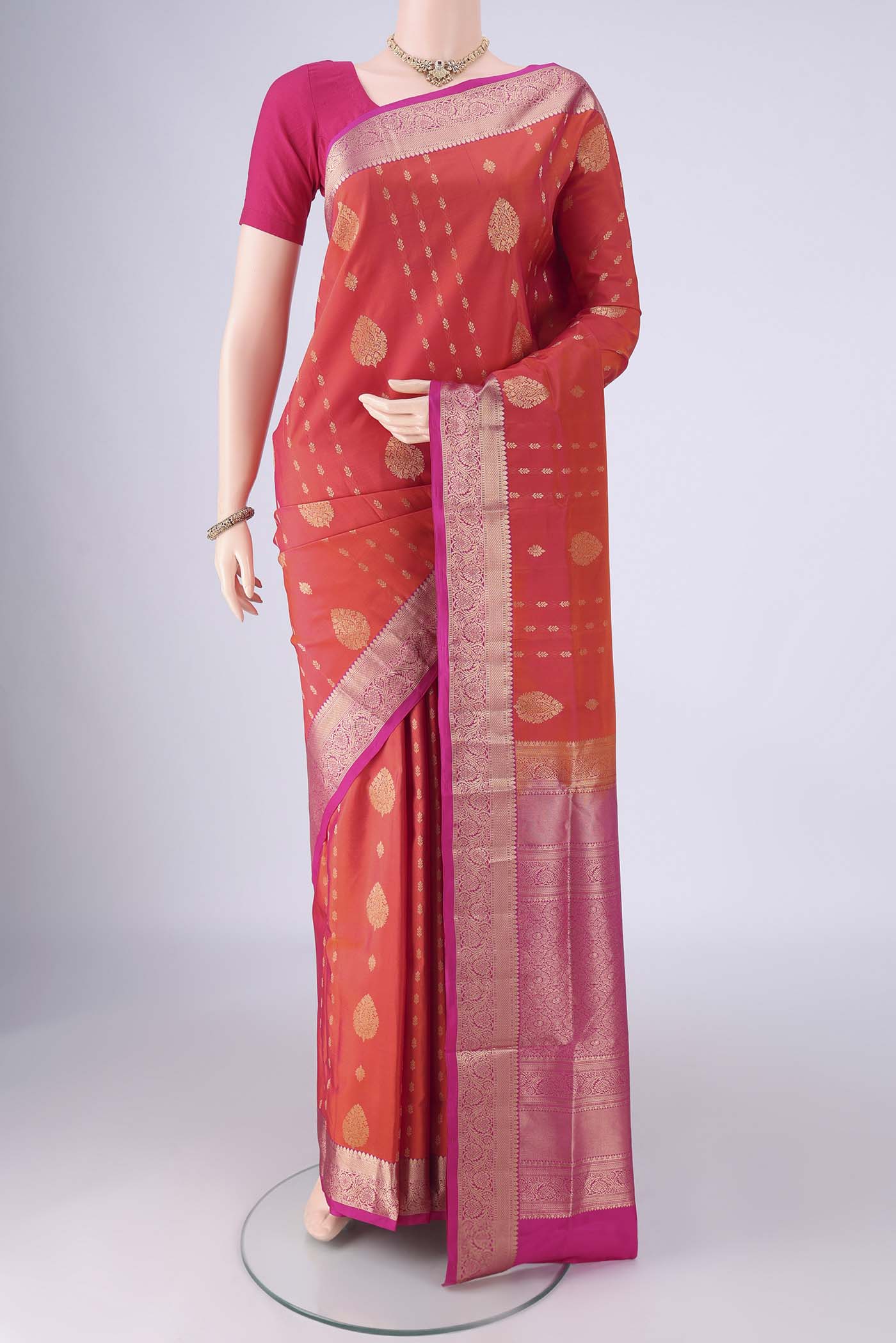 Orange Soft Silk Saree with Zari Butta on the body and Zari Border.  displayed on a mannequin