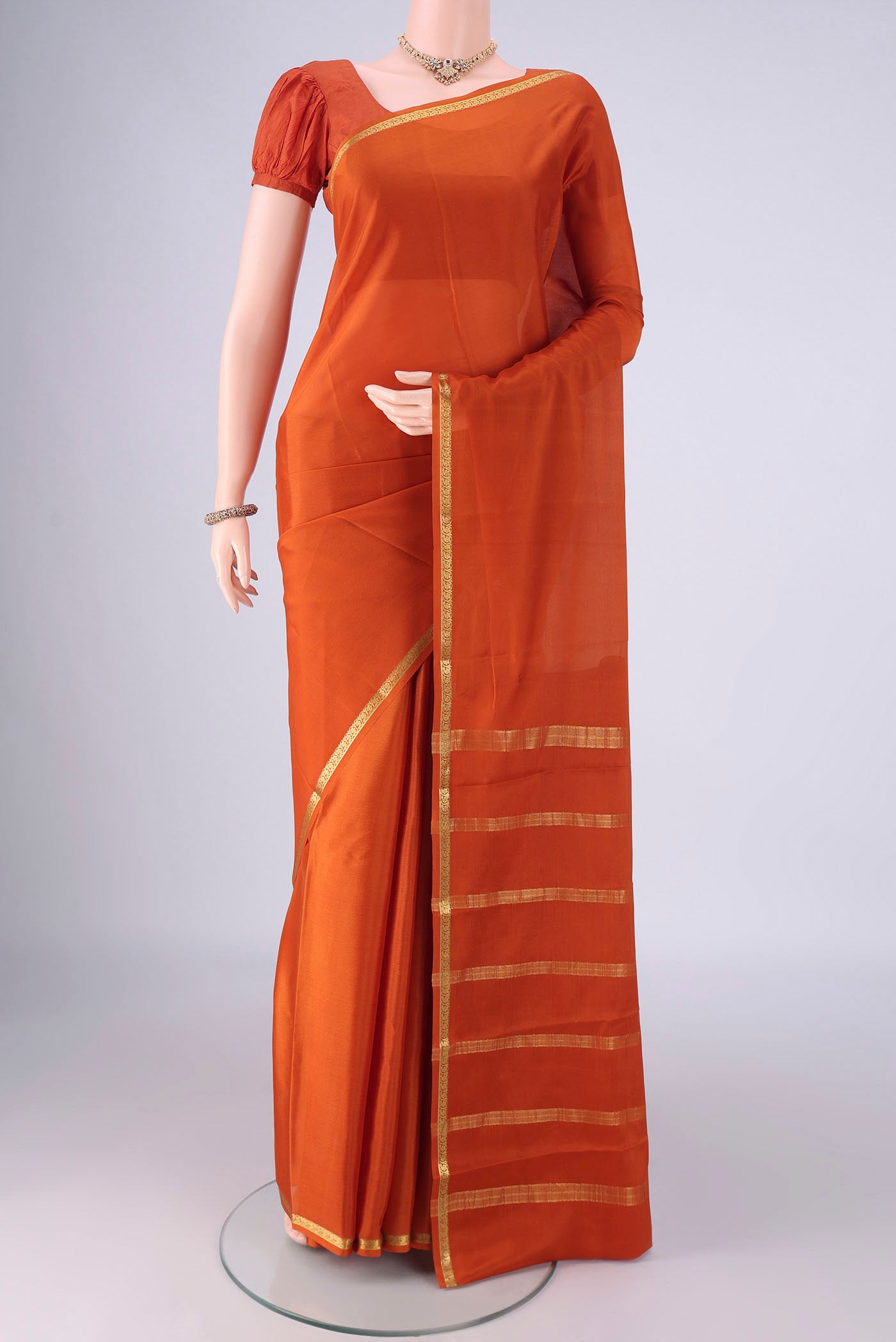 Rust Mysore Crepe Saree with Plain Body and Zari Border.  displayed on a mannequin