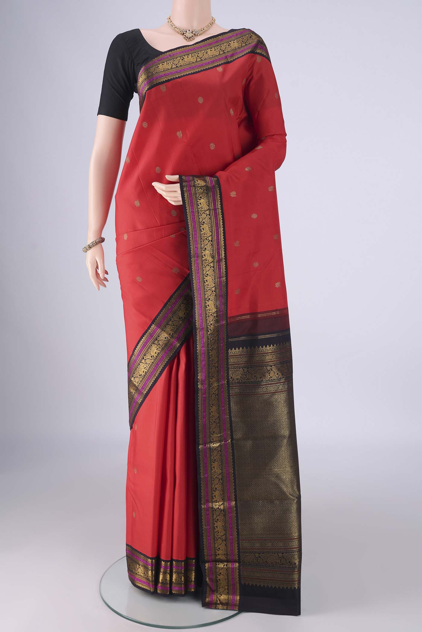 Orange Kanjivaram Silk Saree with Zari Butta on the body and Zari Border.  displayed on a mannequin