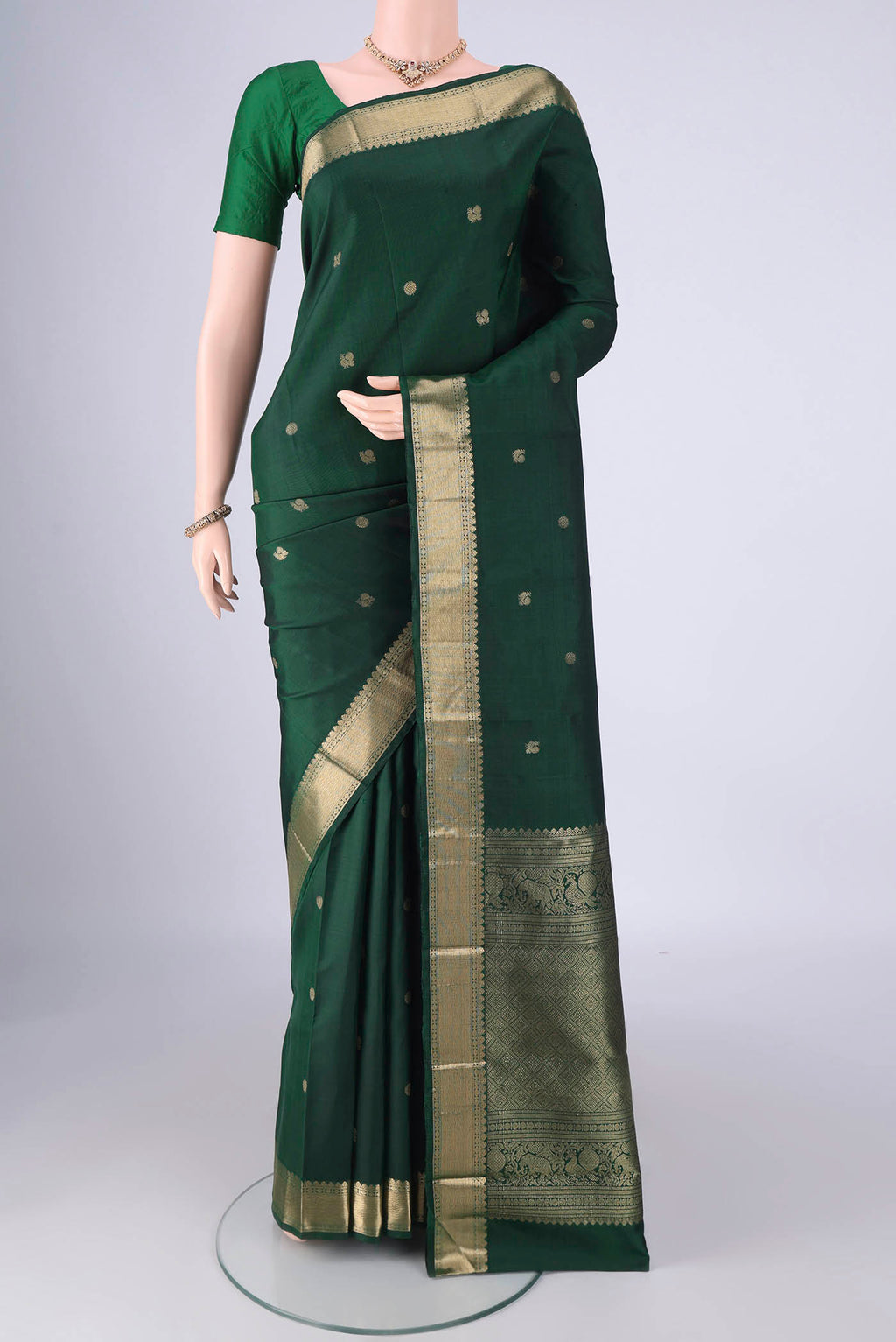 Bottle Green Kanjivaram Silk Saree with Zari Butta on the body and Zari Border.  displayed on a mannequin
