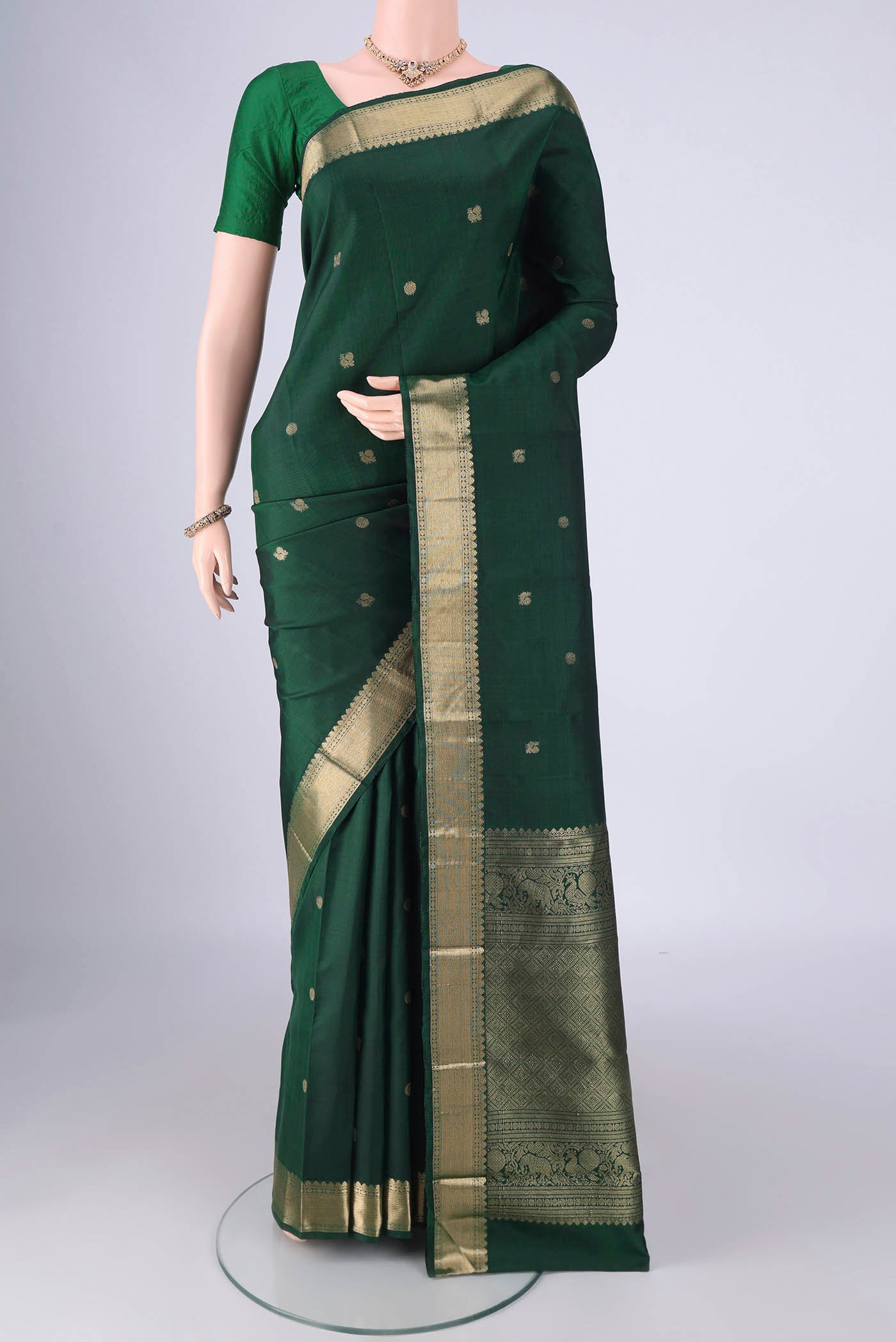 Bottle Green Kanjivaram Silk Saree with Zari Butta on the body and Zari Border.  displayed on a mannequin