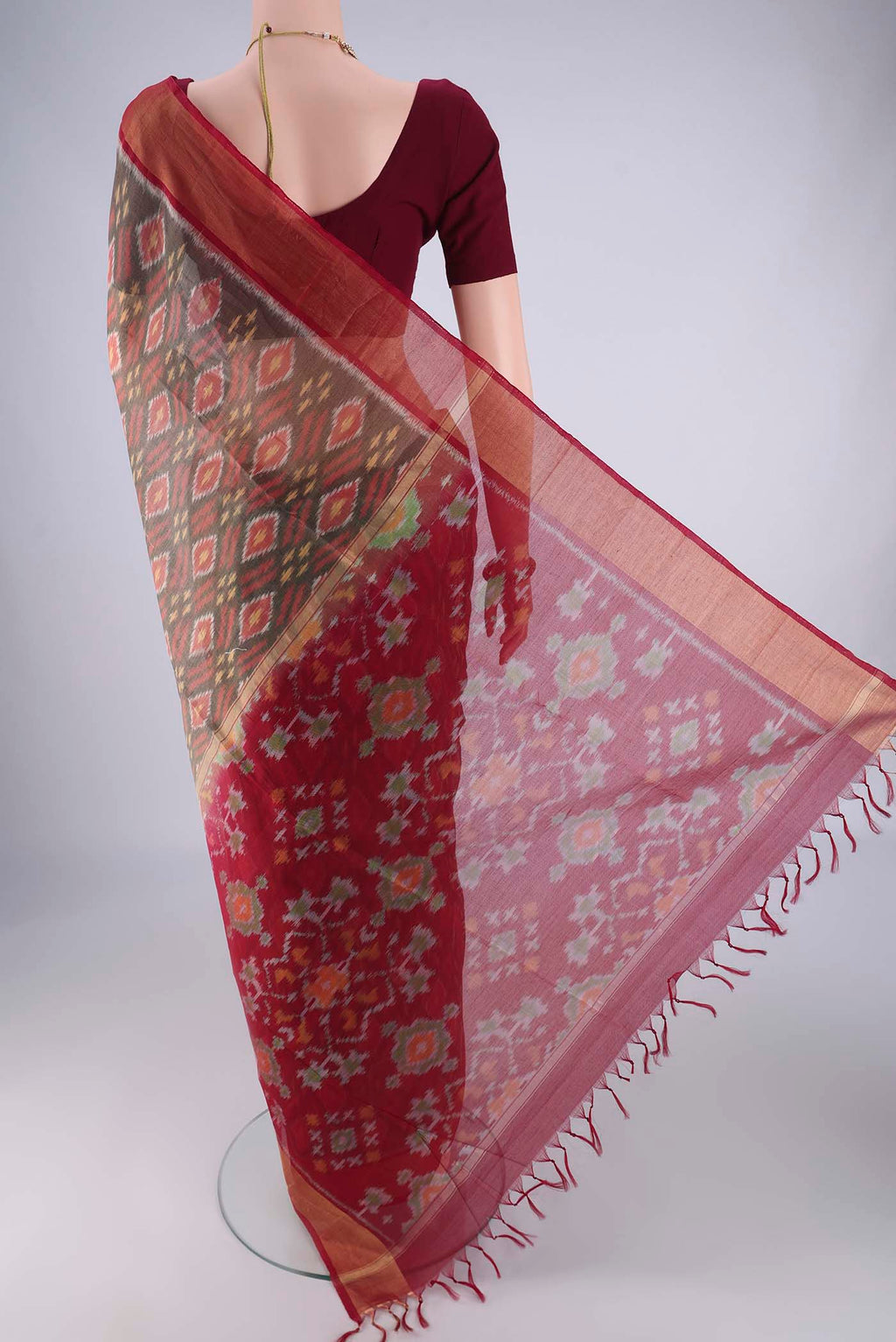 Flat view of Grey Silk Cotton Saree with Ikat design on the body and Zari Border. 
