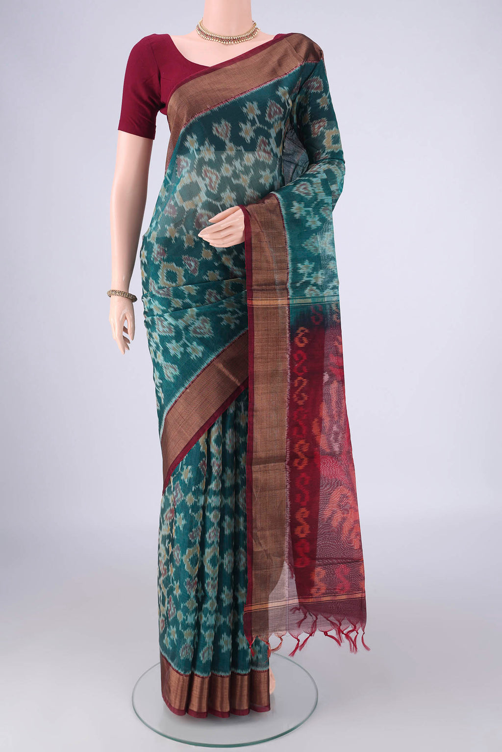 Teal Silk Cotton Saree with Ikat design on the body and Zari Border.  displayed on a mannequin