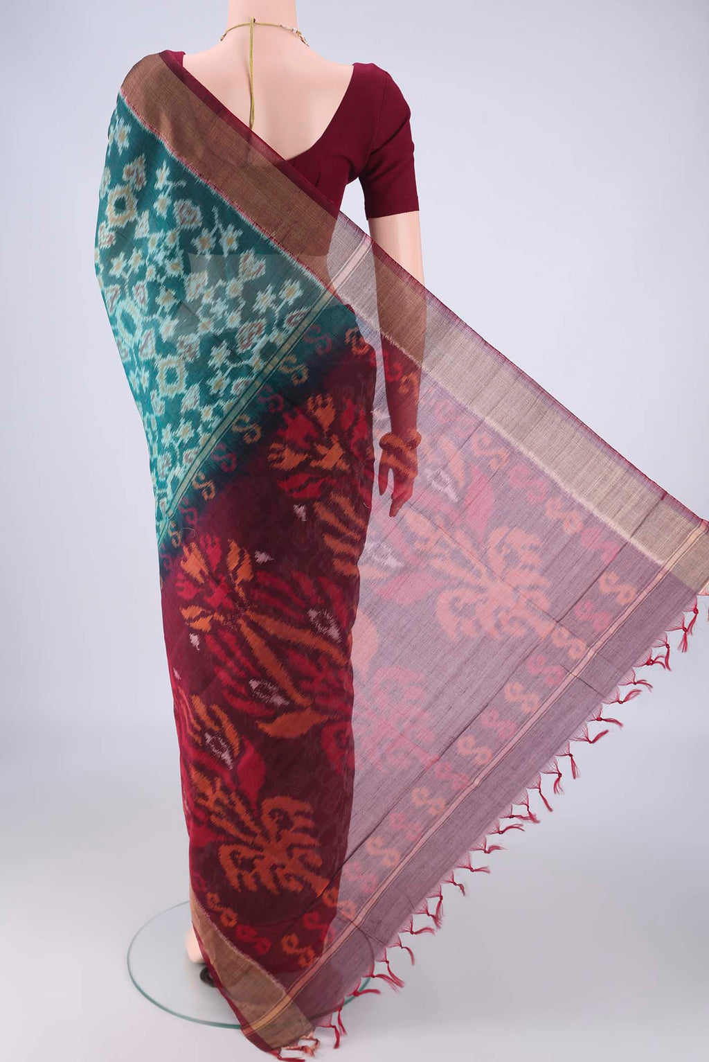 Flat view of Teal Silk Cotton Saree with Ikat design on the body and Zari Border. 