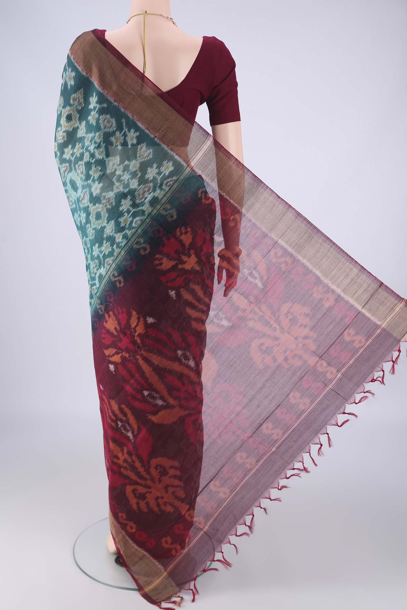 Flat view of Teal Silk Cotton Saree with Ikat design on the body and Zari Border. 