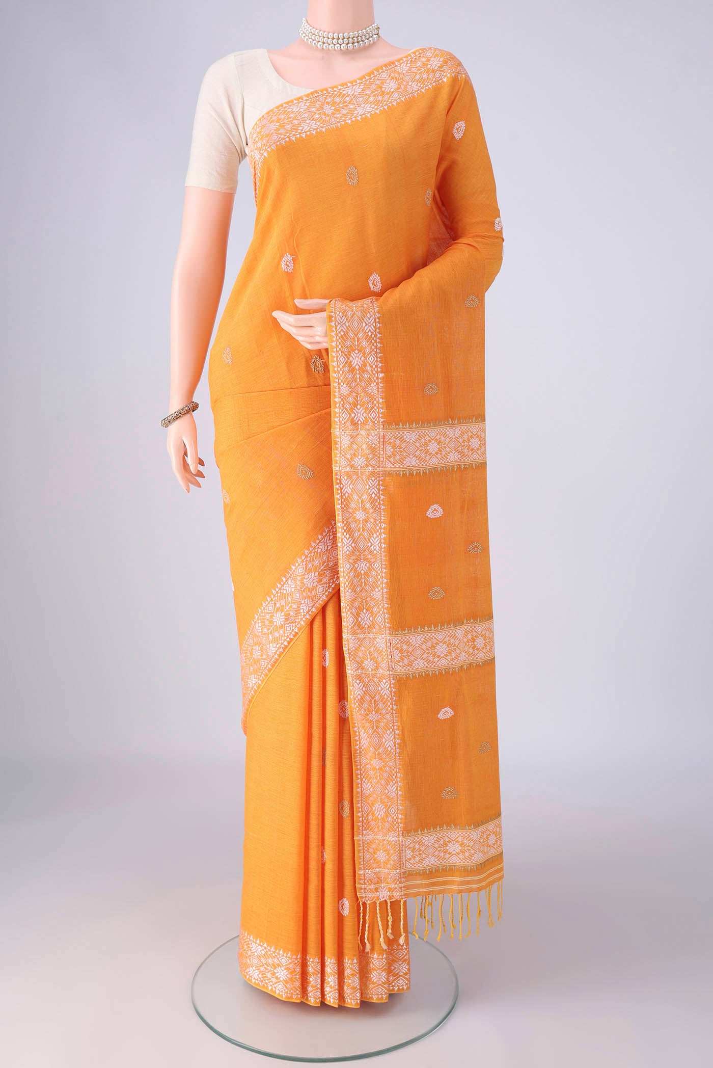Orange Assam Cotton Saree with Thread Butta on the body and Thread Border.  displayed on a mannequin