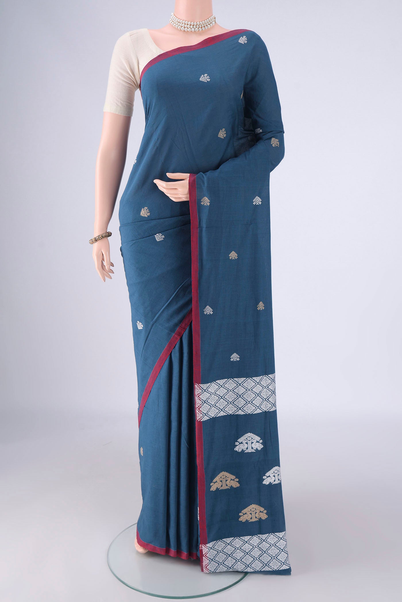 Blue Assam Cotton Saree with Thread Butta on the body and Thread Border.  displayed on a mannequin