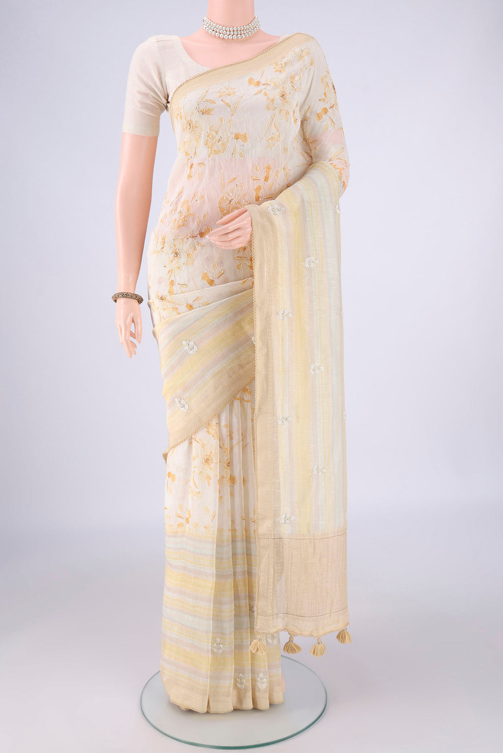 Cream Linen Saree with Embroidery on the body and Zari Border.  displayed on a mannequin