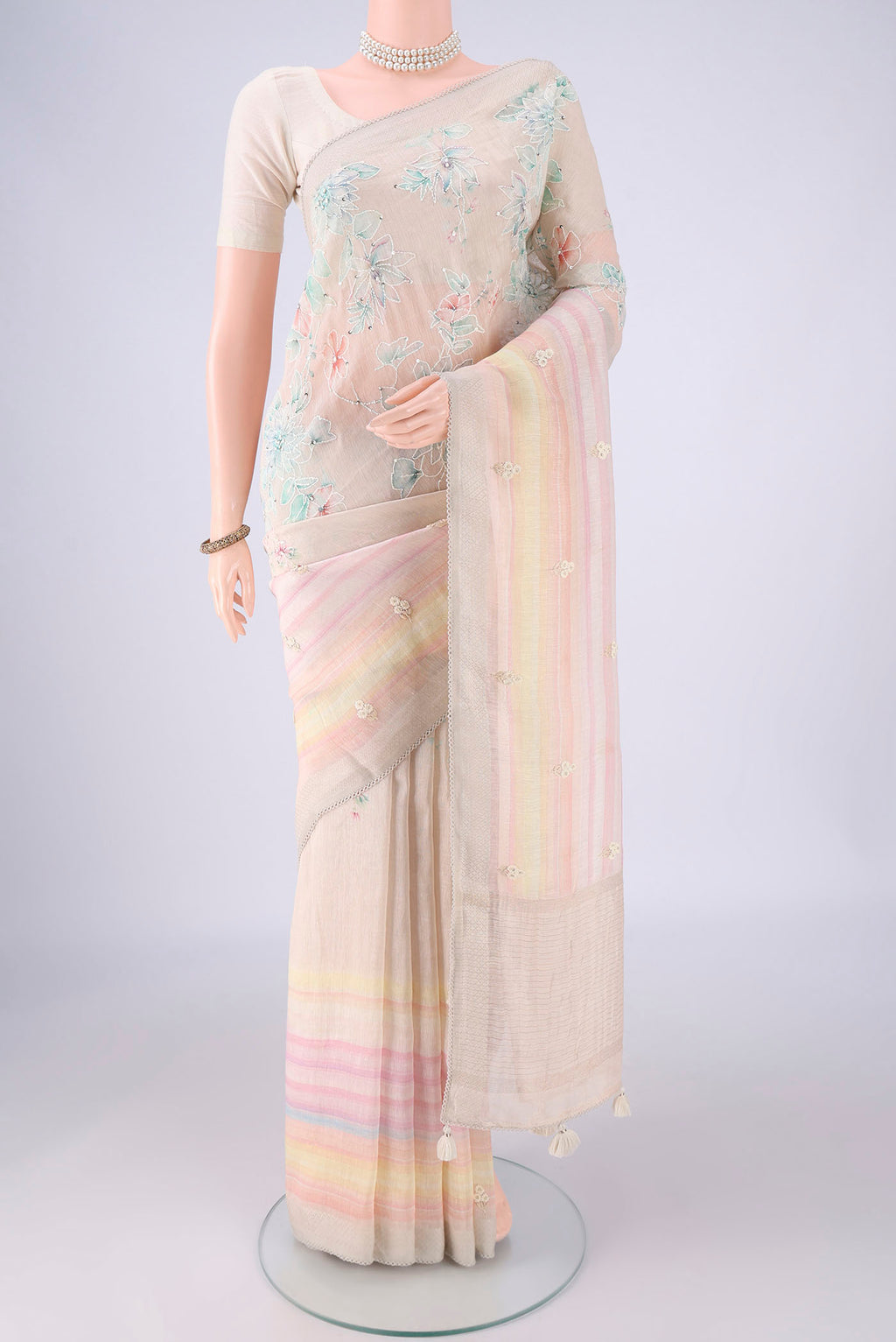 Beige Linen Saree with Embroidery on the body and Zari Border.  displayed on a mannequin