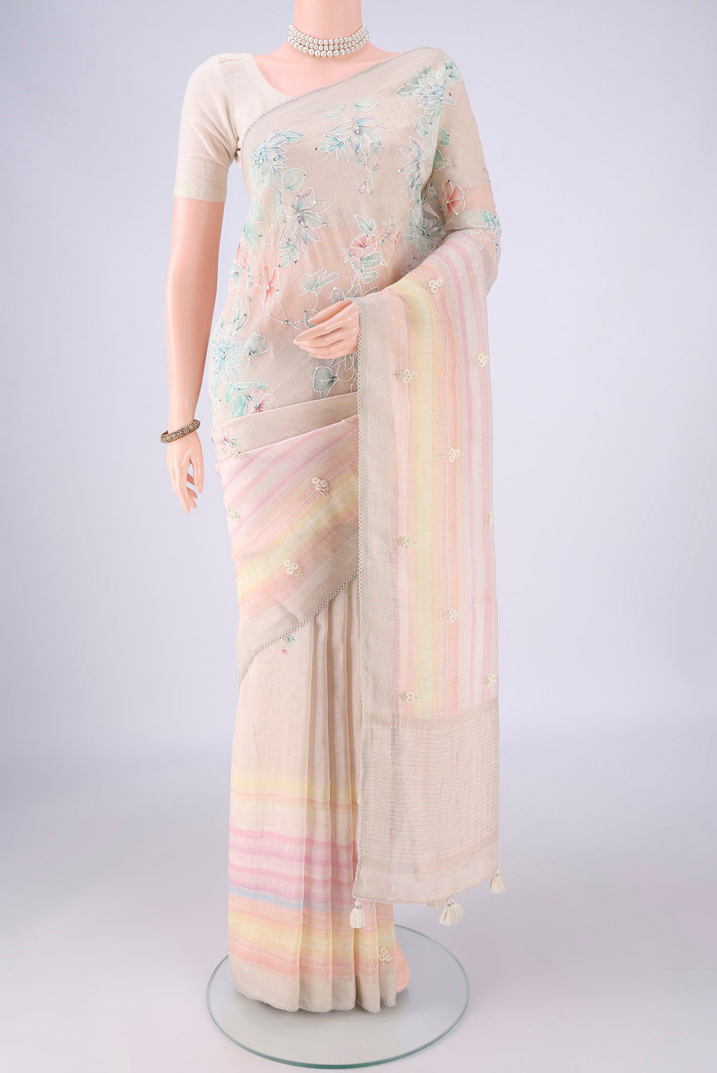 Beige Linen Saree with Embroidery on the body and Zari Border.  displayed on a mannequin