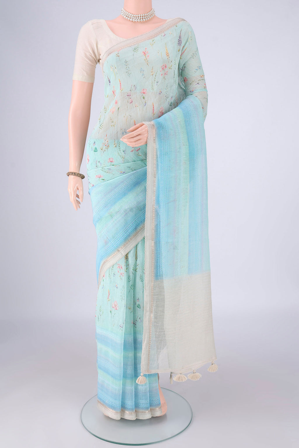 Sky Blue Linen Saree with Printed design on the body and Zari Border.  displayed on a mannequin
