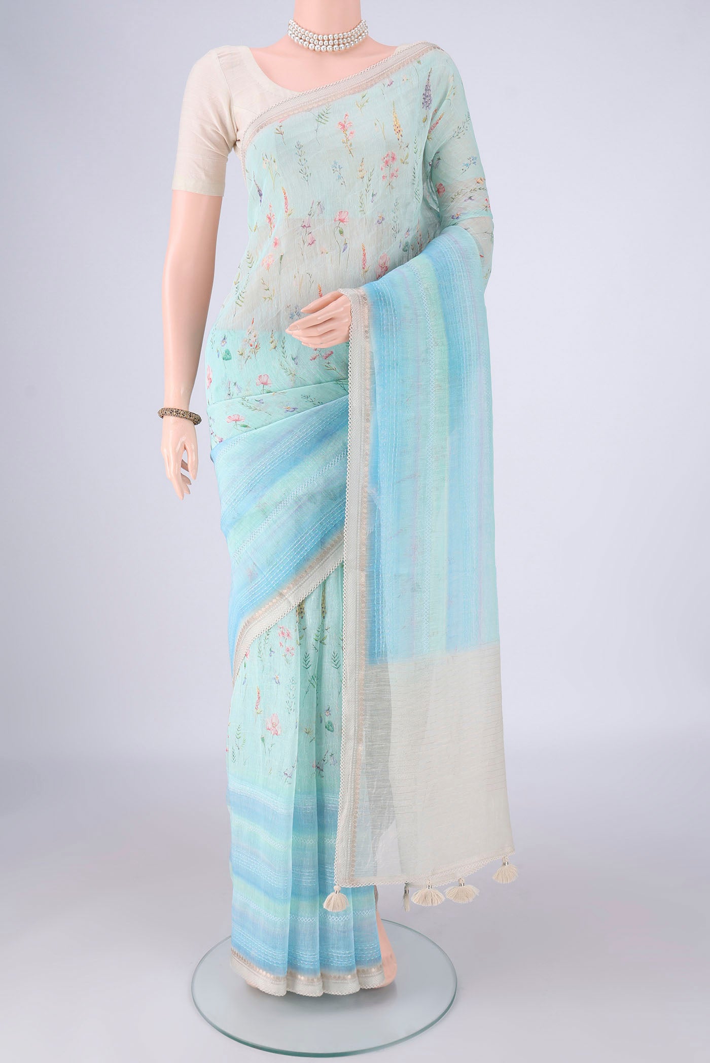 Sky Blue Linen Saree with Printed design on the body and Zari Border.  displayed on a mannequin