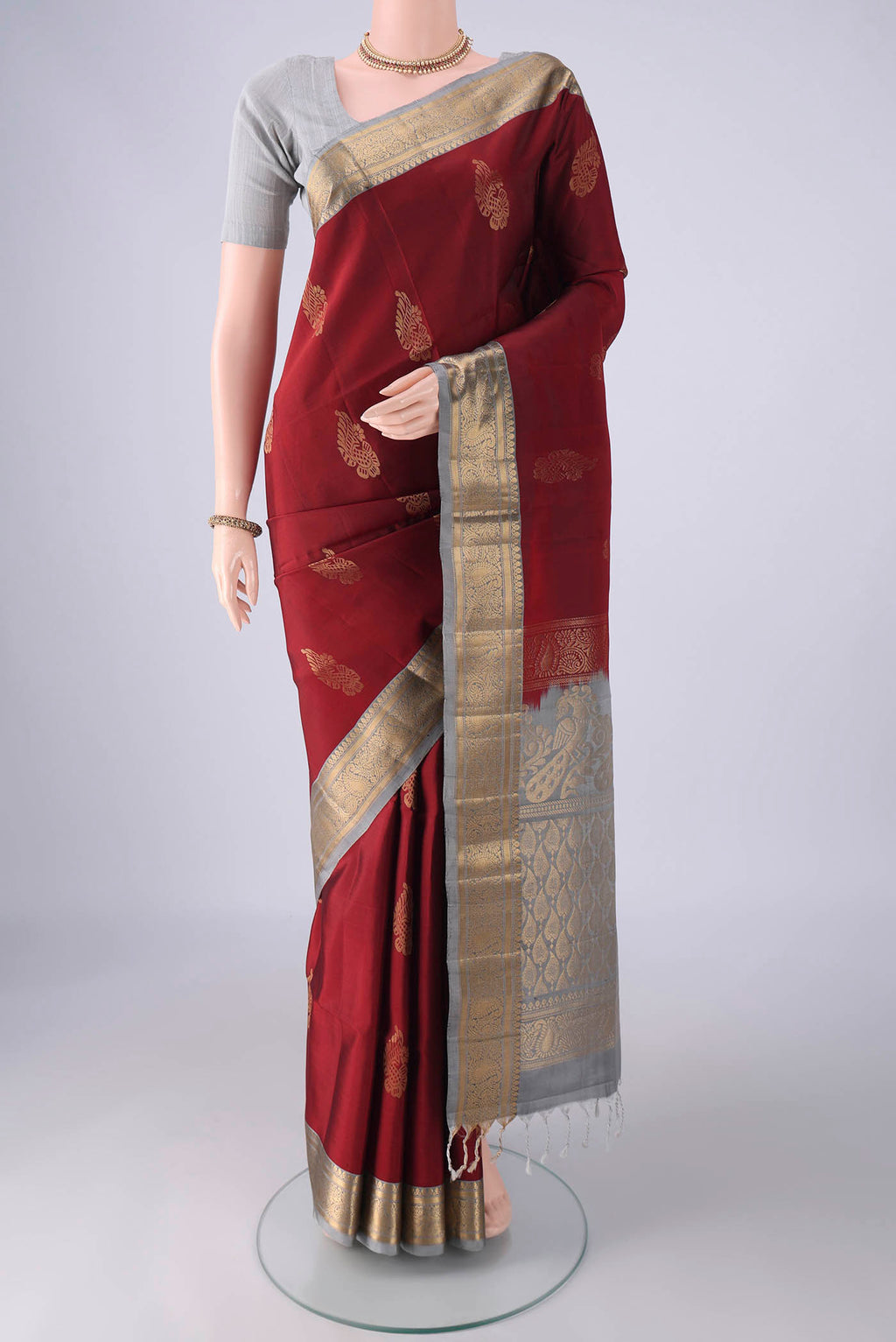 Maroon Soft Silk Saree with Zari Butta on the body and Zari Border.  displayed on a mannequin