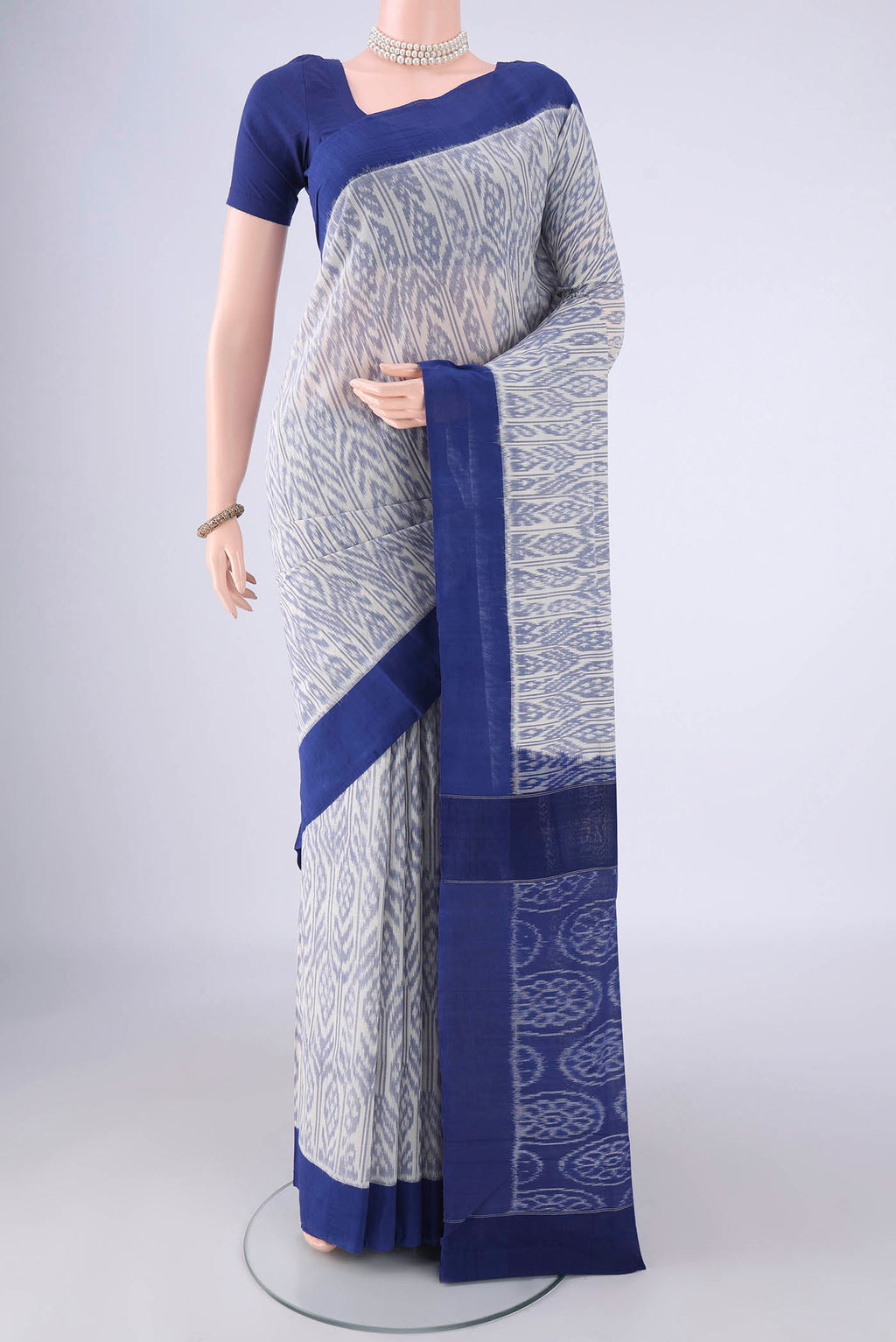 White Pochampally Cotton Saree with Ikat design on the body and Plain Border.  displayed on a mannequin